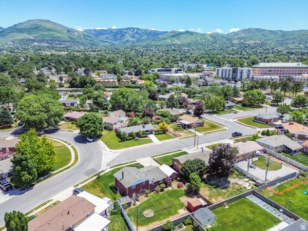 Aerial perspective showcasing a residential area with mature trees and mountain backdrops
