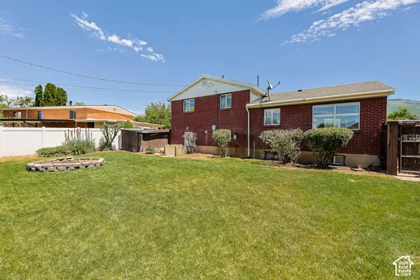 Expansive green lawn with a structured garden bed and a white vinyl fence
