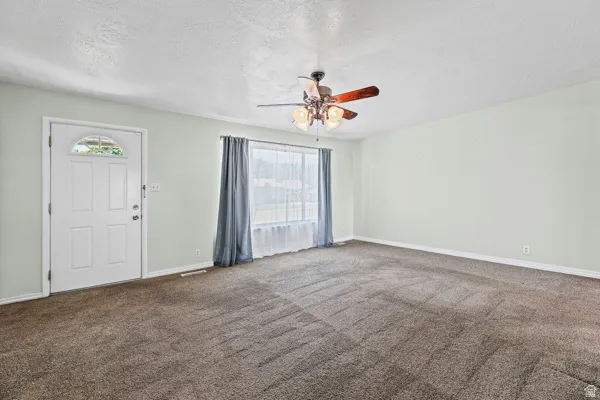 Spacious interior room featuring light-colored walls and brown carpeting