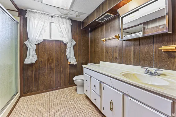 Bathroom featuring wood-paneled walls and a white vanity with an integrated sink