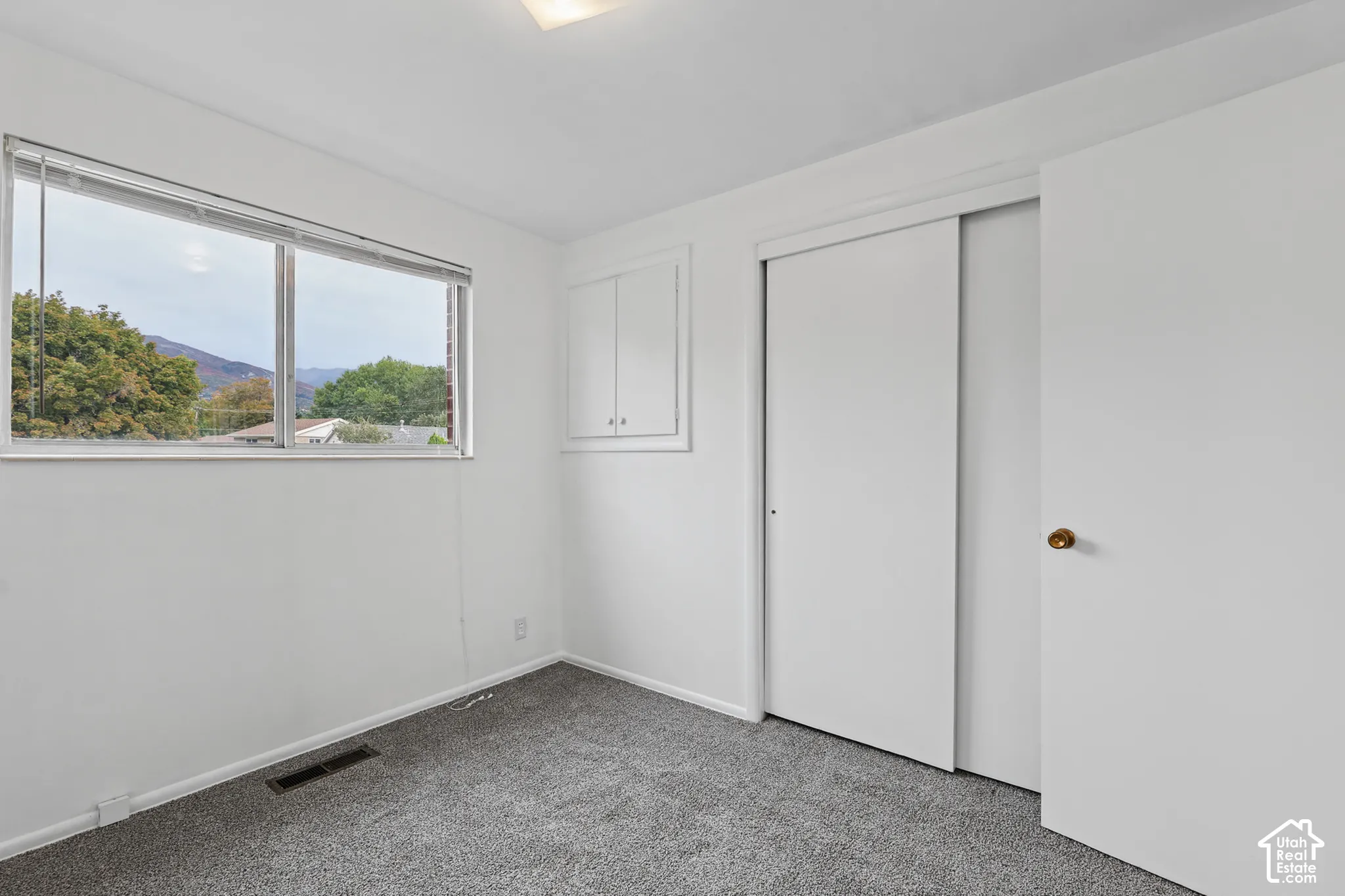 Bedroom 1 recessed lighting, grey carpet flooring, white walls, built-in cabinetry, and a window with mountain scenery