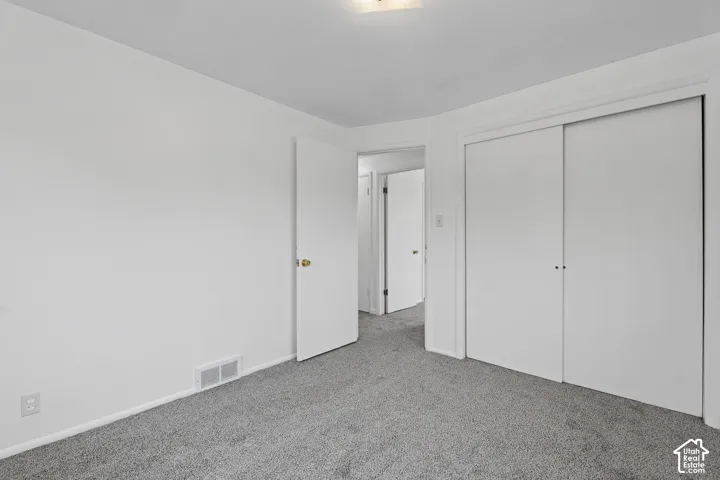 Bedroom 3 Plush grey carpeting with clean white walls and trim, featuring a sliding double-door closet