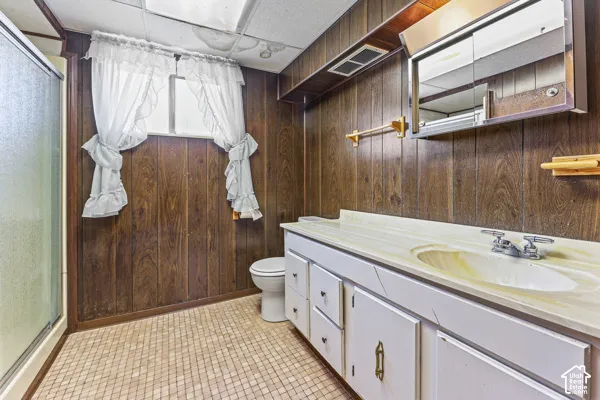 Bathroom featuring wood-paneled walls and a white vanity with an integrated sink