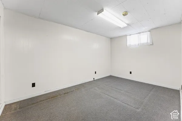 Bedroom 4 Carpeted room featuring white paneling walls and a drop ceiling with fluorescent lighting