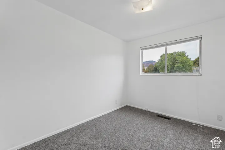 Bedroom 1 Neutral wall color, carpeted flooring, and a large window
