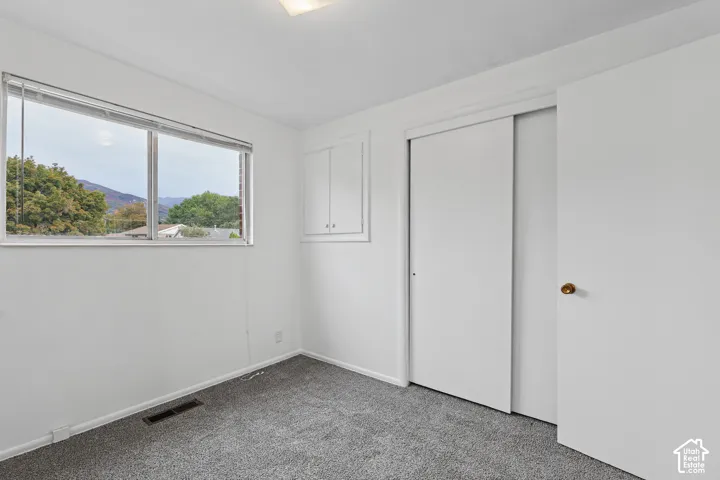 Bedroom 1 recessed lighting, grey carpet flooring, white walls, built-in cabinetry, and a window with mountain scenery