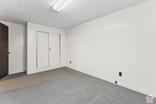 Bedroom 4 Room featuring light gray carpet, white painted walls, white trim, a built-in closet with sliding doors, and an overhead fluorescent light fixture