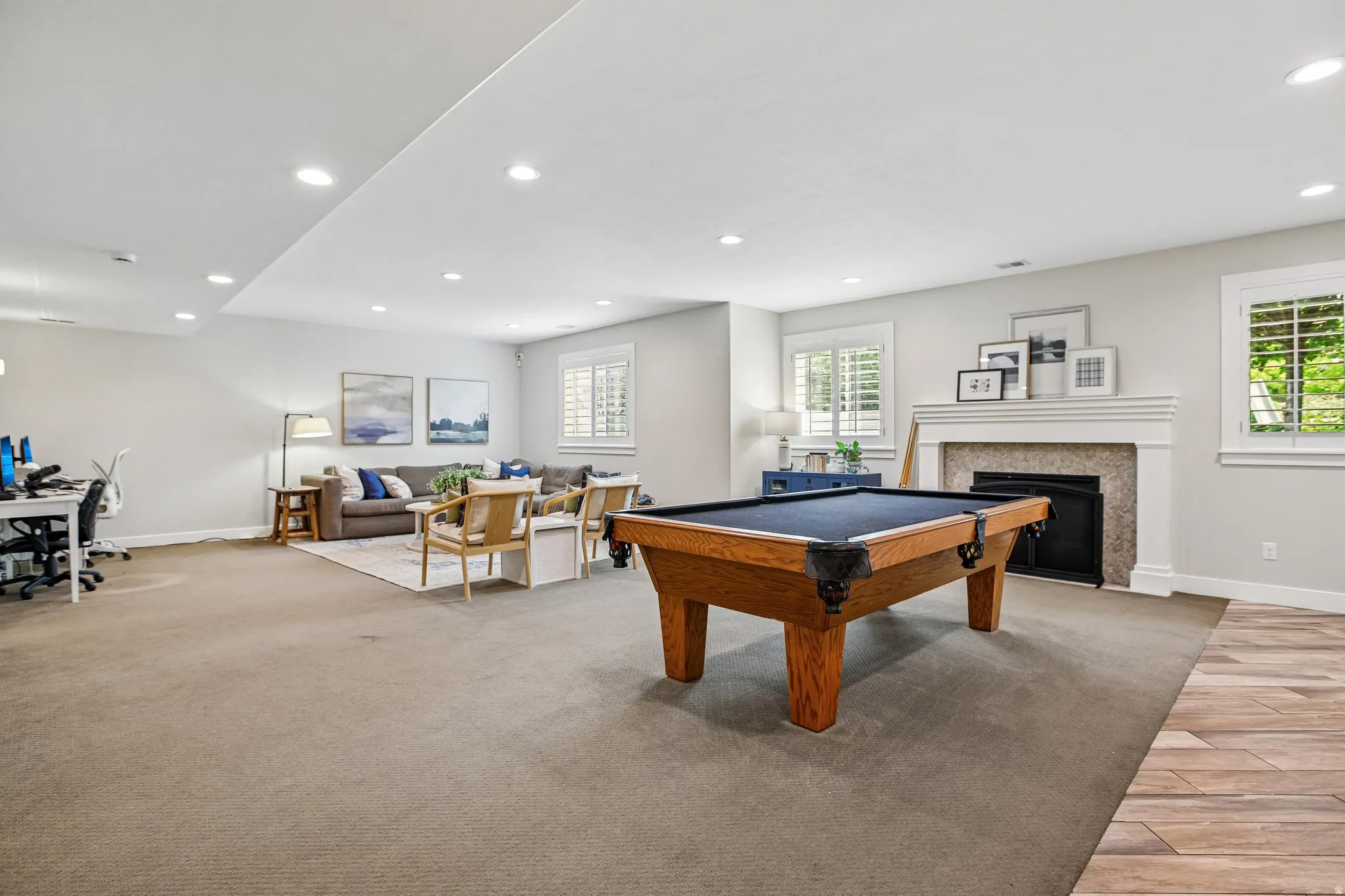 Spacious room featuring recessed lighting and a fireplace with a white mantel and stone surround
