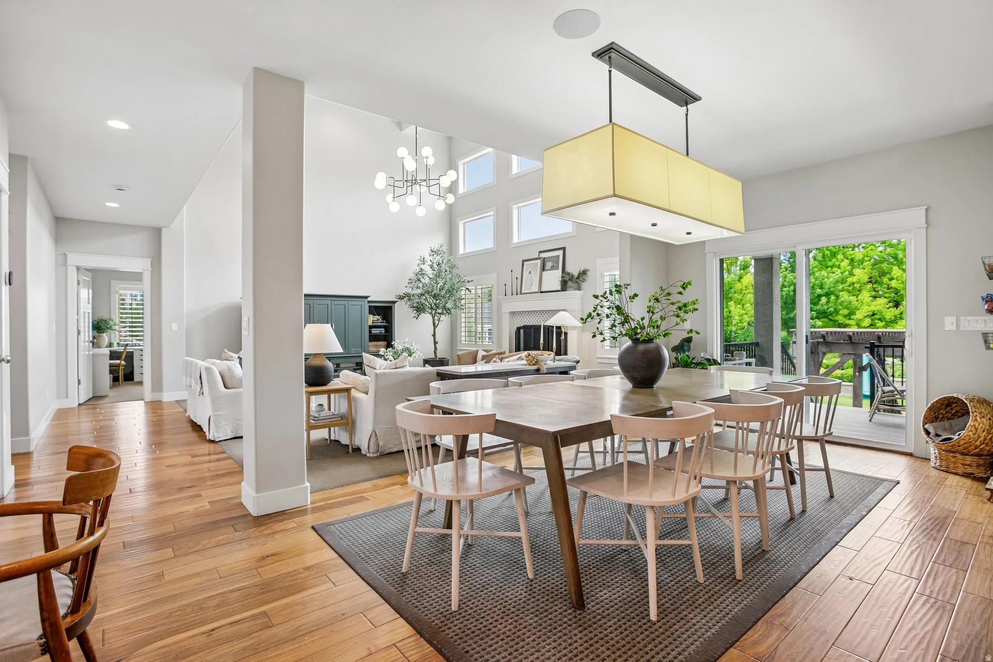 Dining area featuring a contemporary rectangular chandelier, wood-finish flooring, and direct access to an outdoor deck