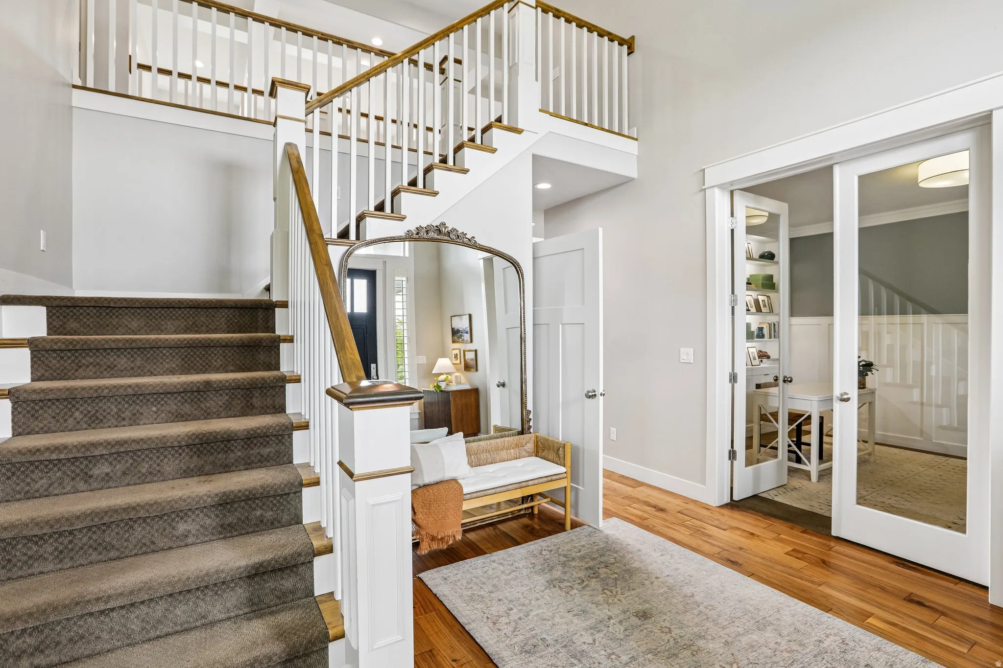 Hardwood flooring entry featuring a multi-level staircase with carpeted treads and white balusters