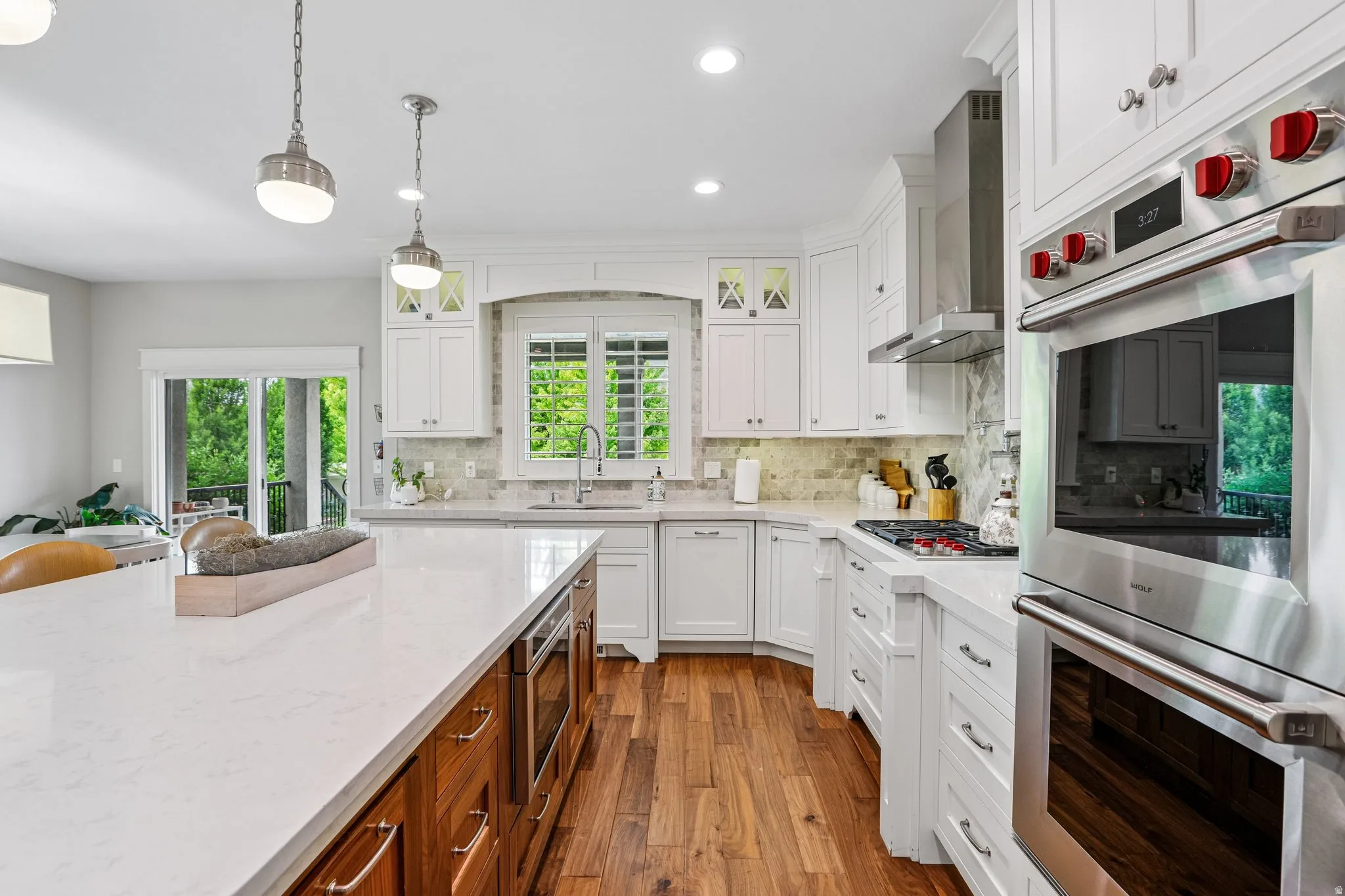Gourmet kitchen featuring white cabinetry, light countertops, wood-finish flooring, a built-in double oven, and stainless steel appliances