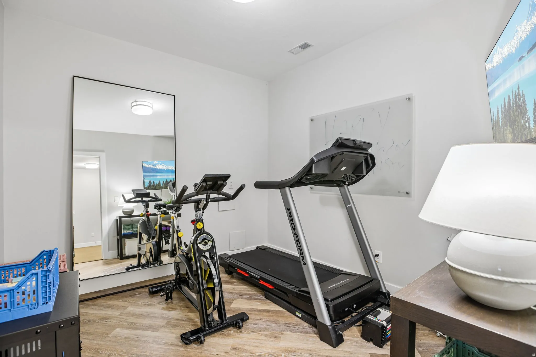 Versatile room featuring wood-finish flooring, recessed lighting, and a full-length mirror