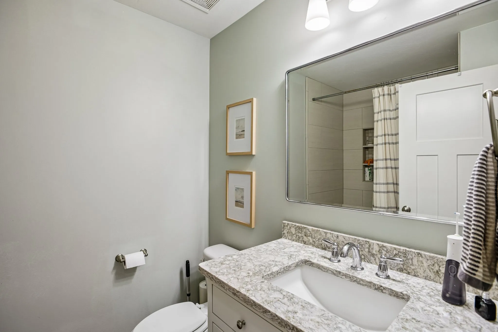 Bathroom vanity with a white rectangular undermount sink, chrome faucet, and a light-toned stone countertop