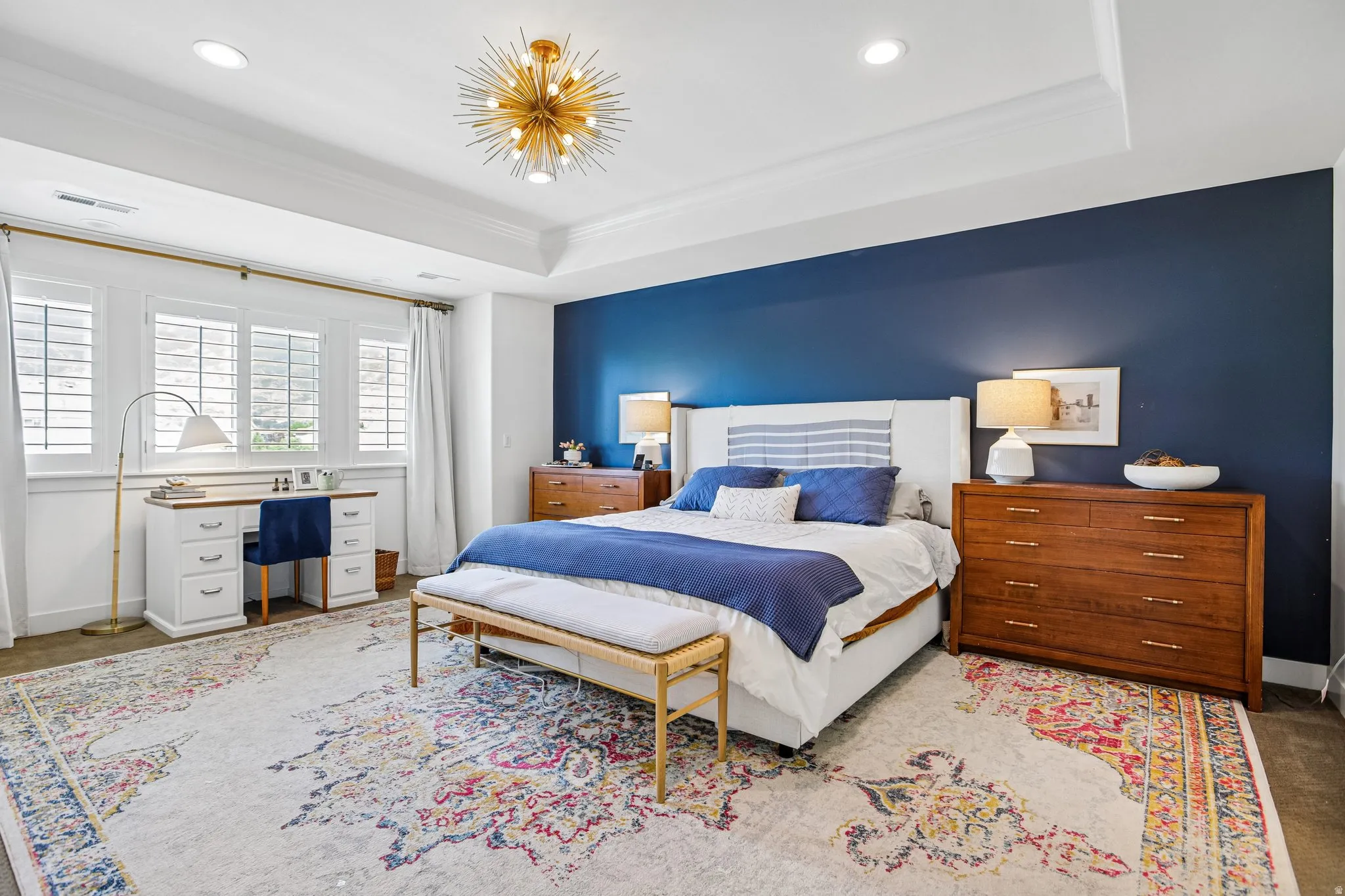Spacious bedroom featuring a tray ceiling, recessed lighting, and a modern sputnik chandelier
