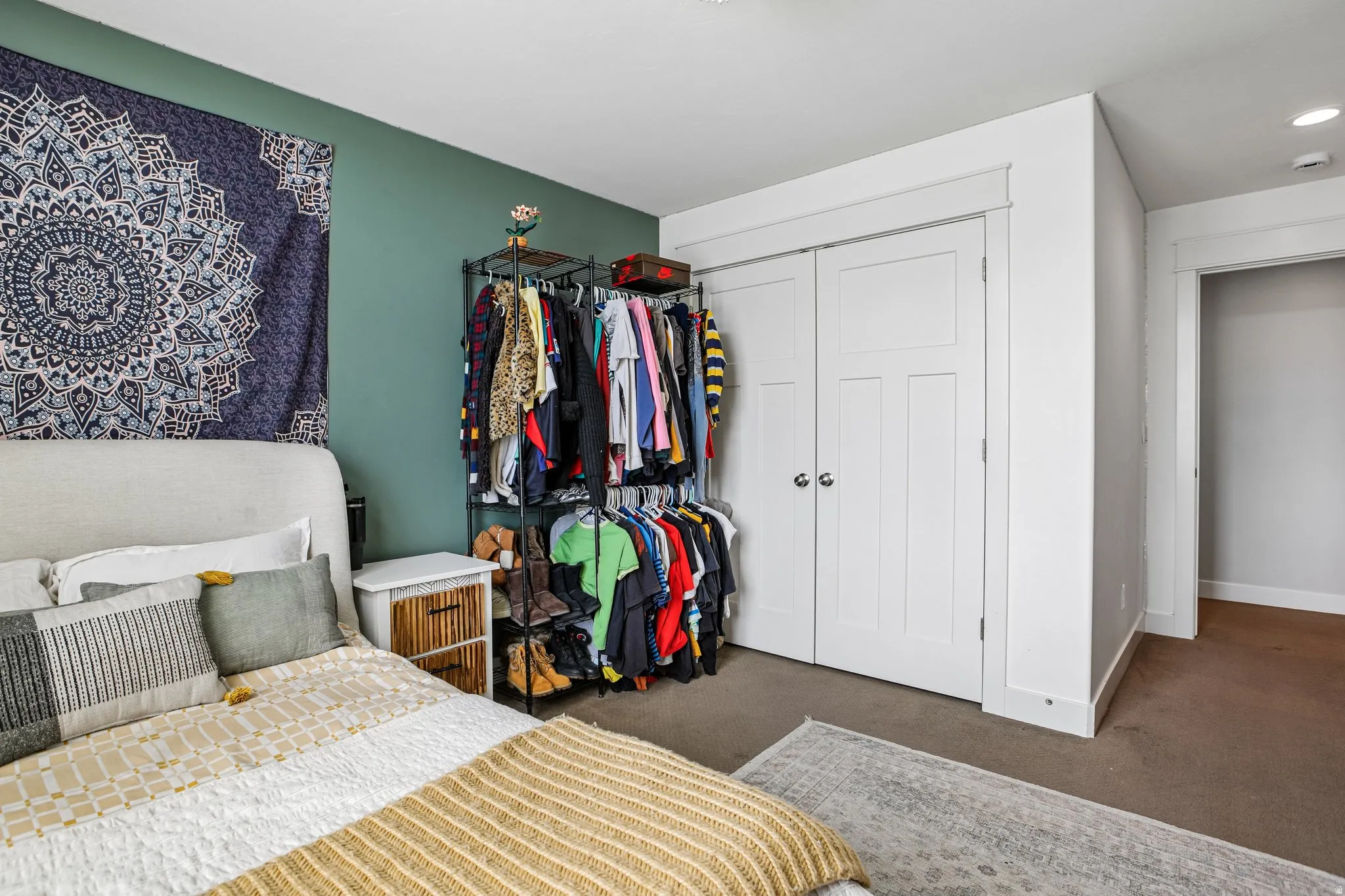 Bedroom featuring a plush upholstered headboard, white trim, and a vibrant accent wall