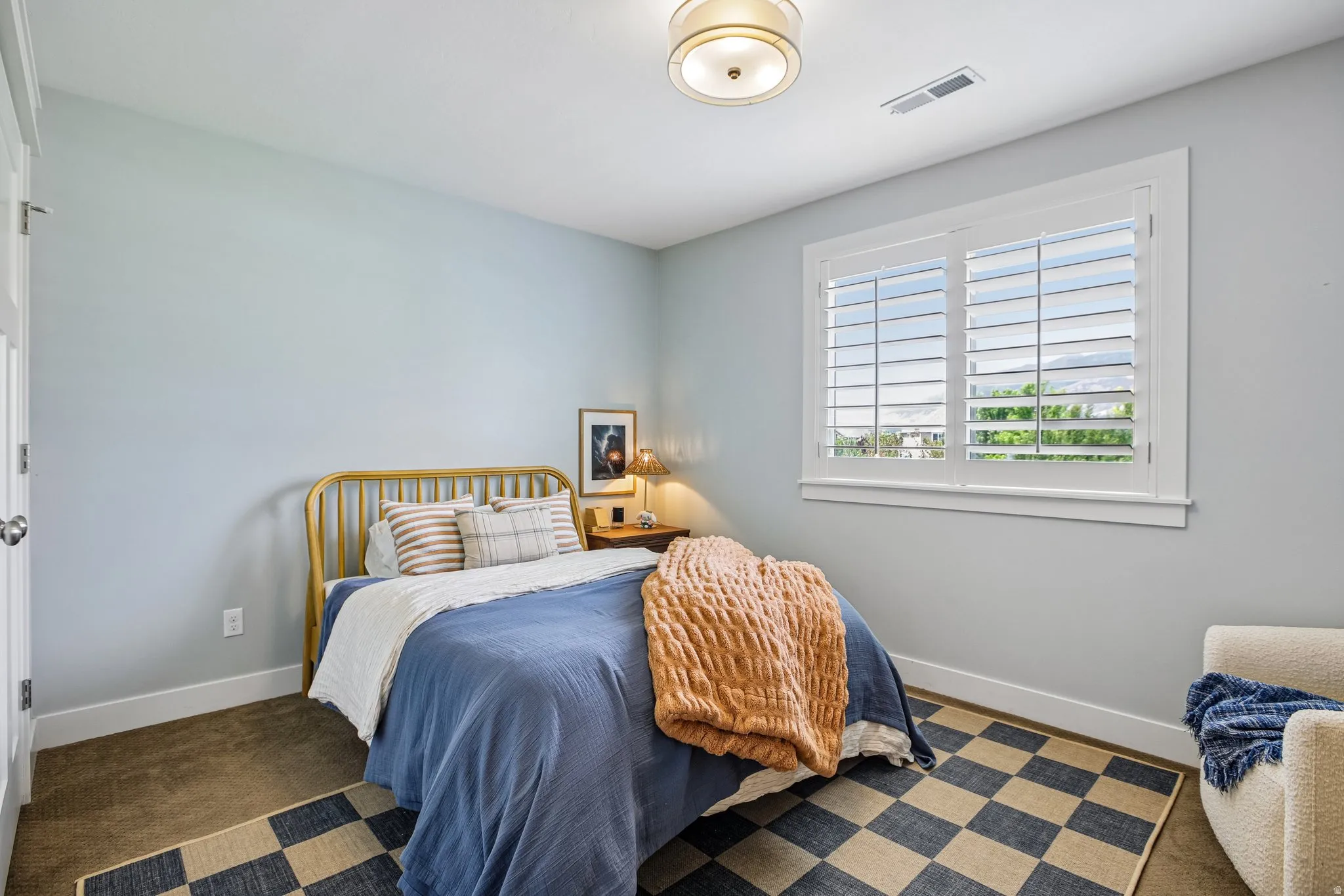 Room featuring a single window with white plantation shutters, light blue walls, and a ceiling-mounted drum light fixture