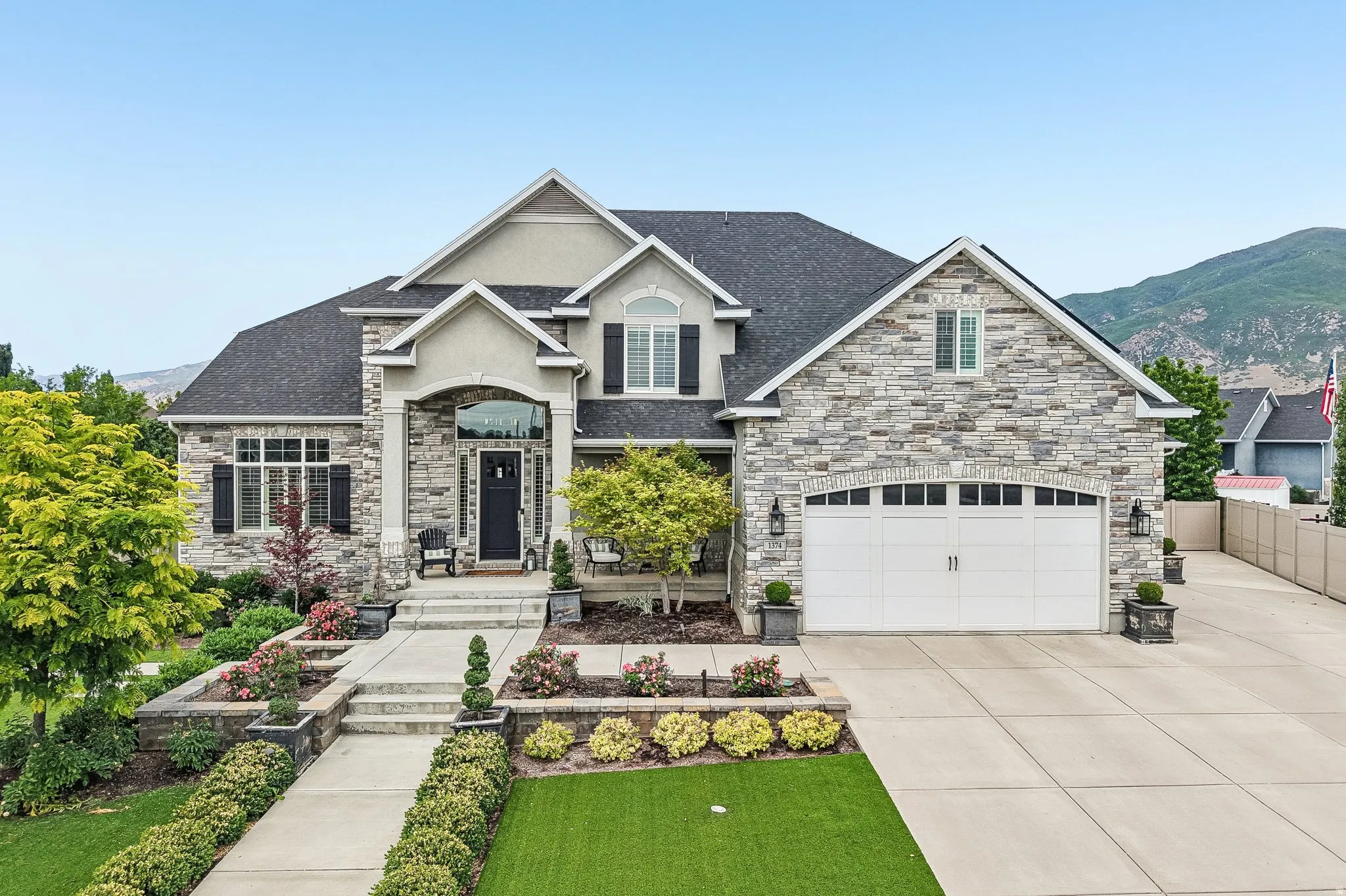 Stately residence featuring a stone and stucco exterior, arched portico entry, and a prominent two-car garage with arched windows
