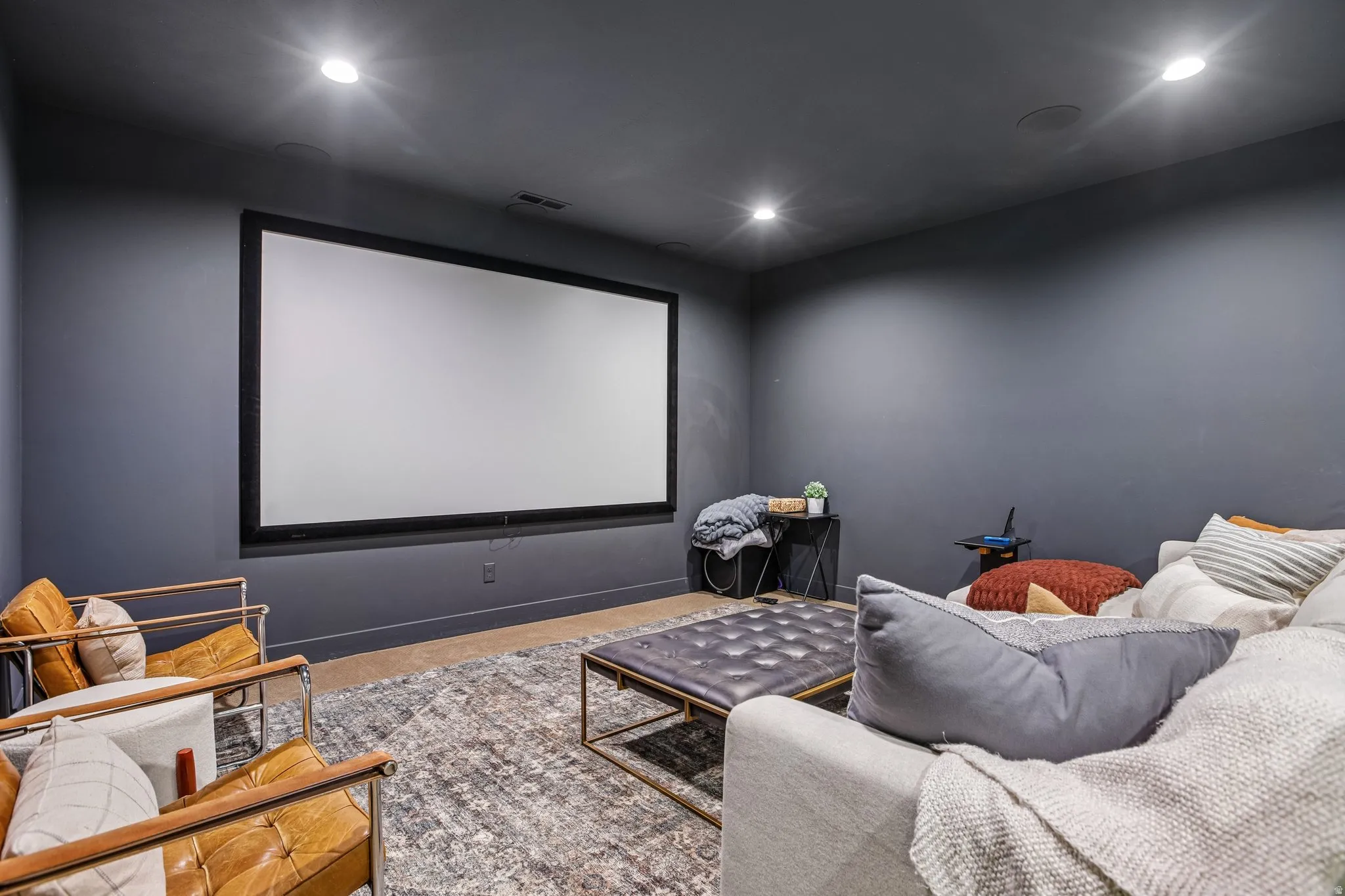 Dedicated home theater featuring a large projection screen, recessed lighting, and wall-mounted speakers
