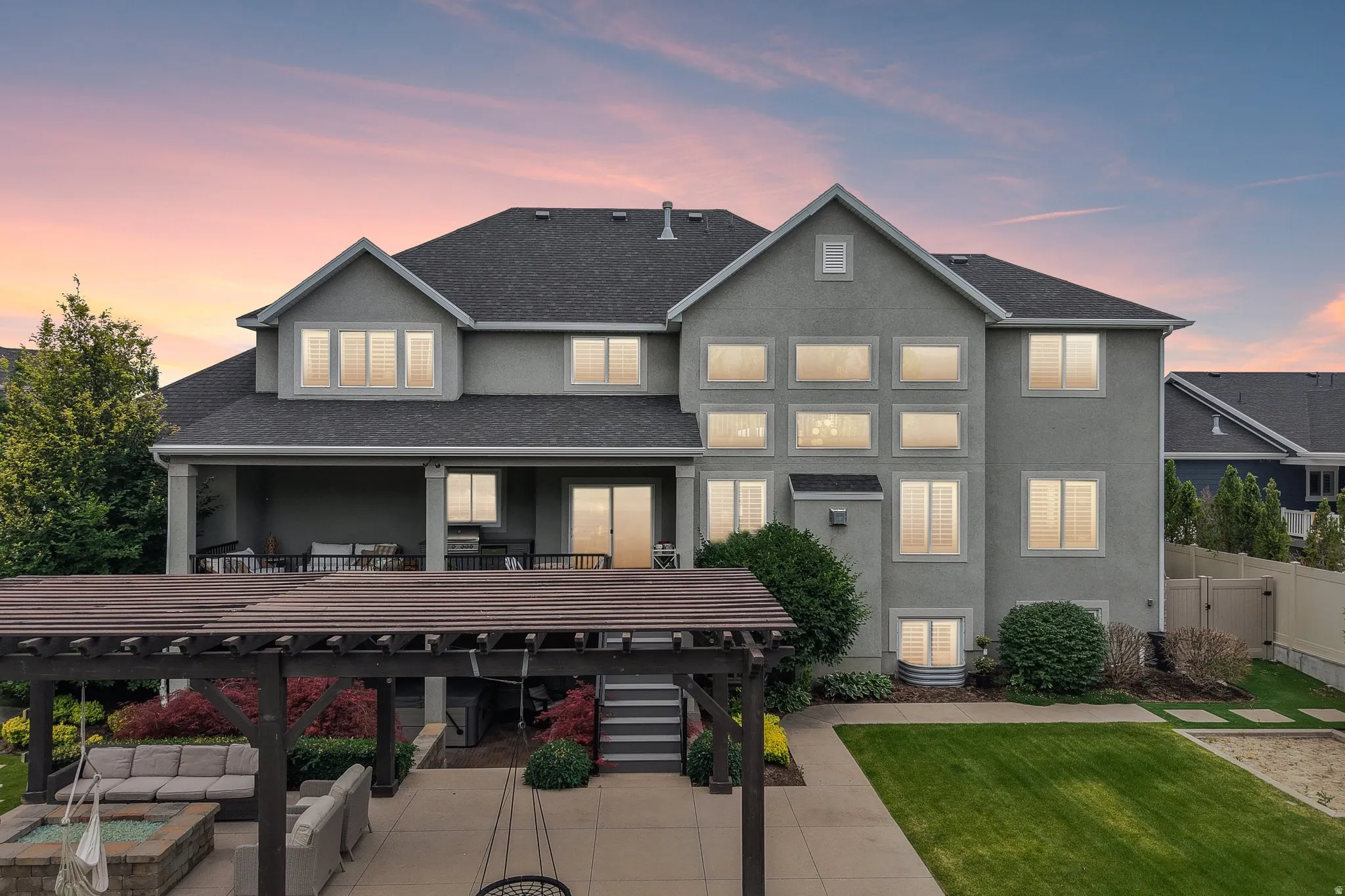 Rear exterior featuring a covered patio, multi-level windows, a dark shingle roof, and a wood pergola over a patio