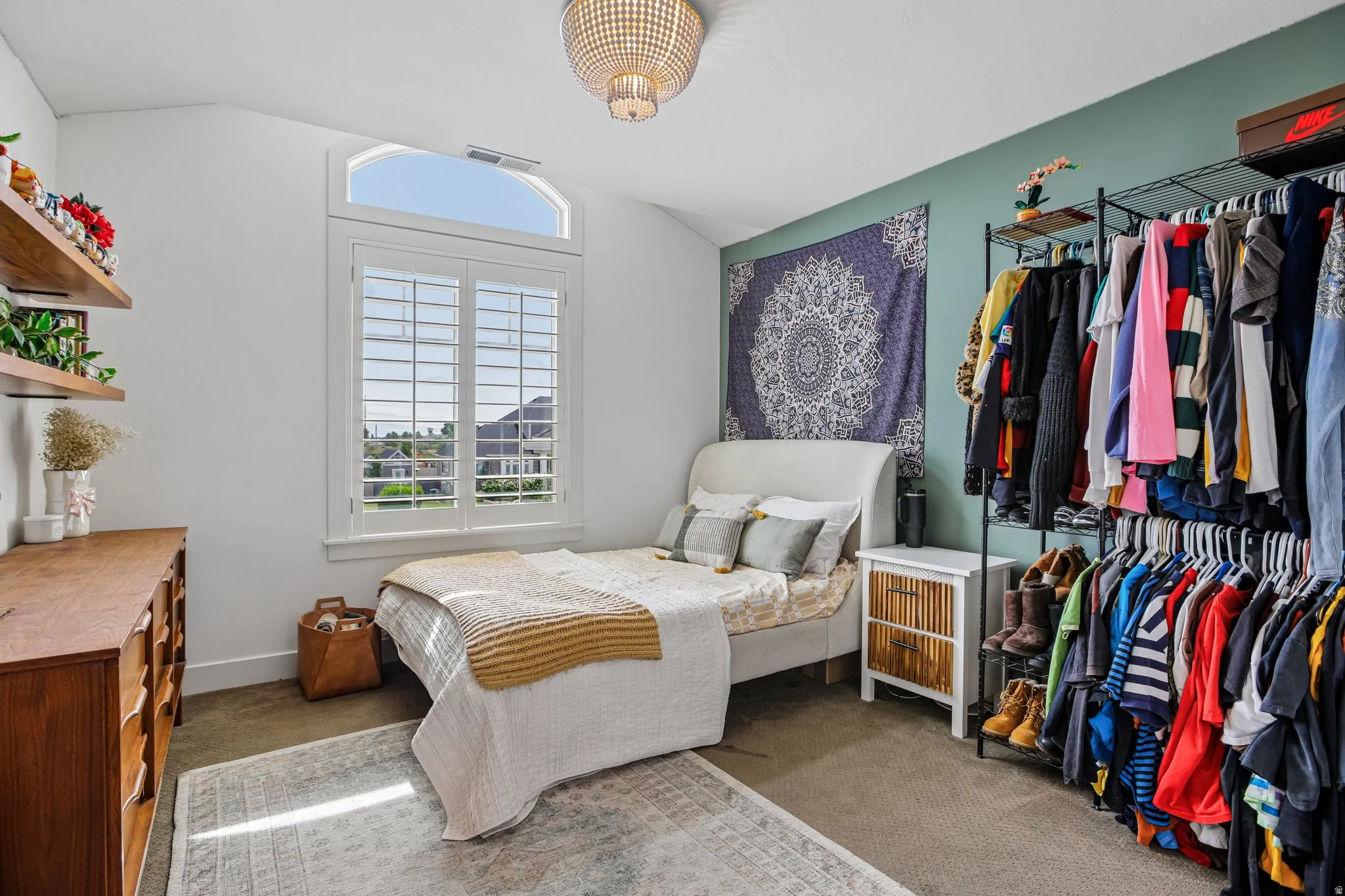 Vaulted ceiling with an arched window, plantation shutters, and a decorative ceiling fixture