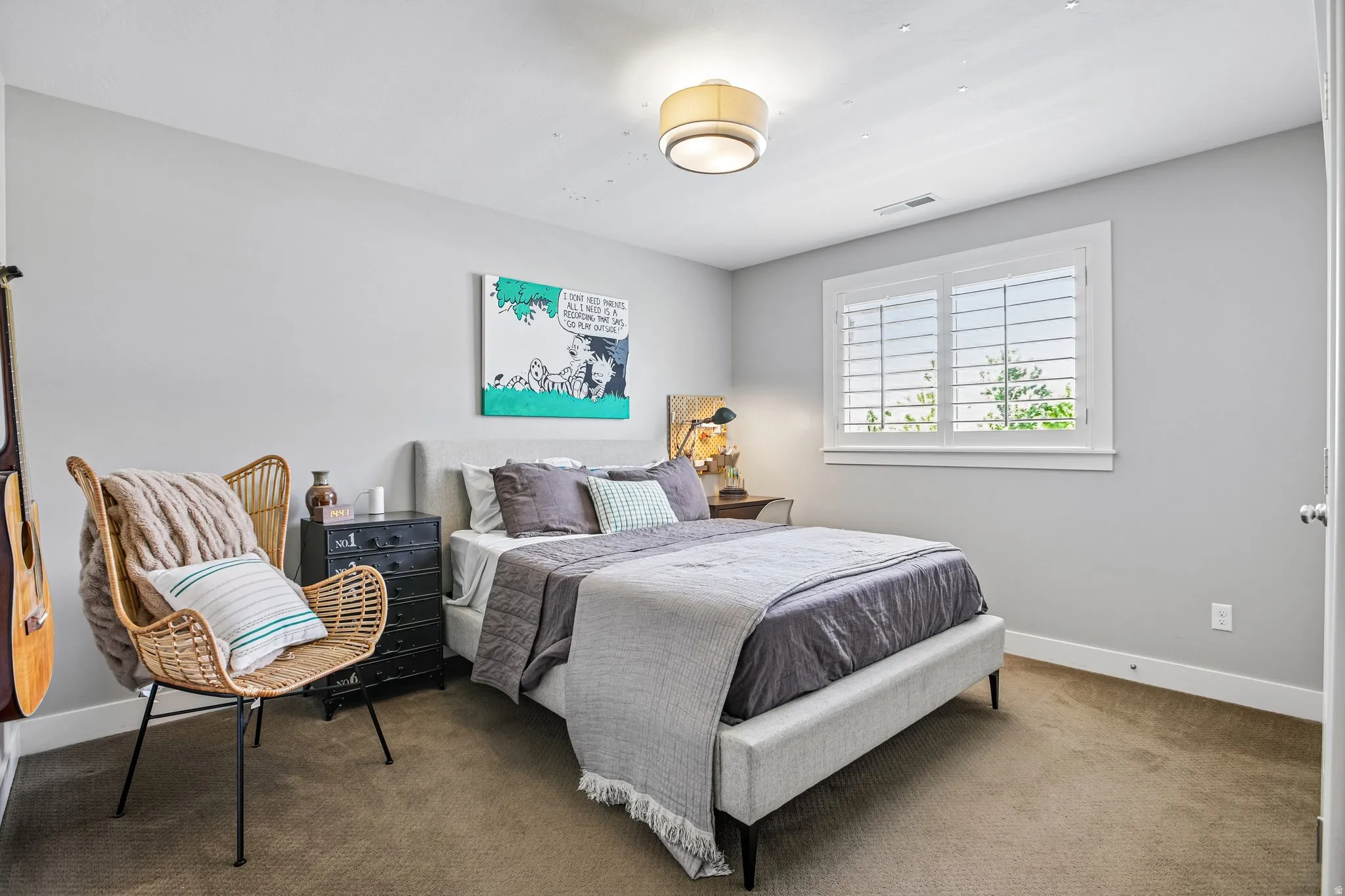 Carpeted bedroom featuring a window with white plantation shutters, a contemporary flush-mount ceiling light, and ample natural light