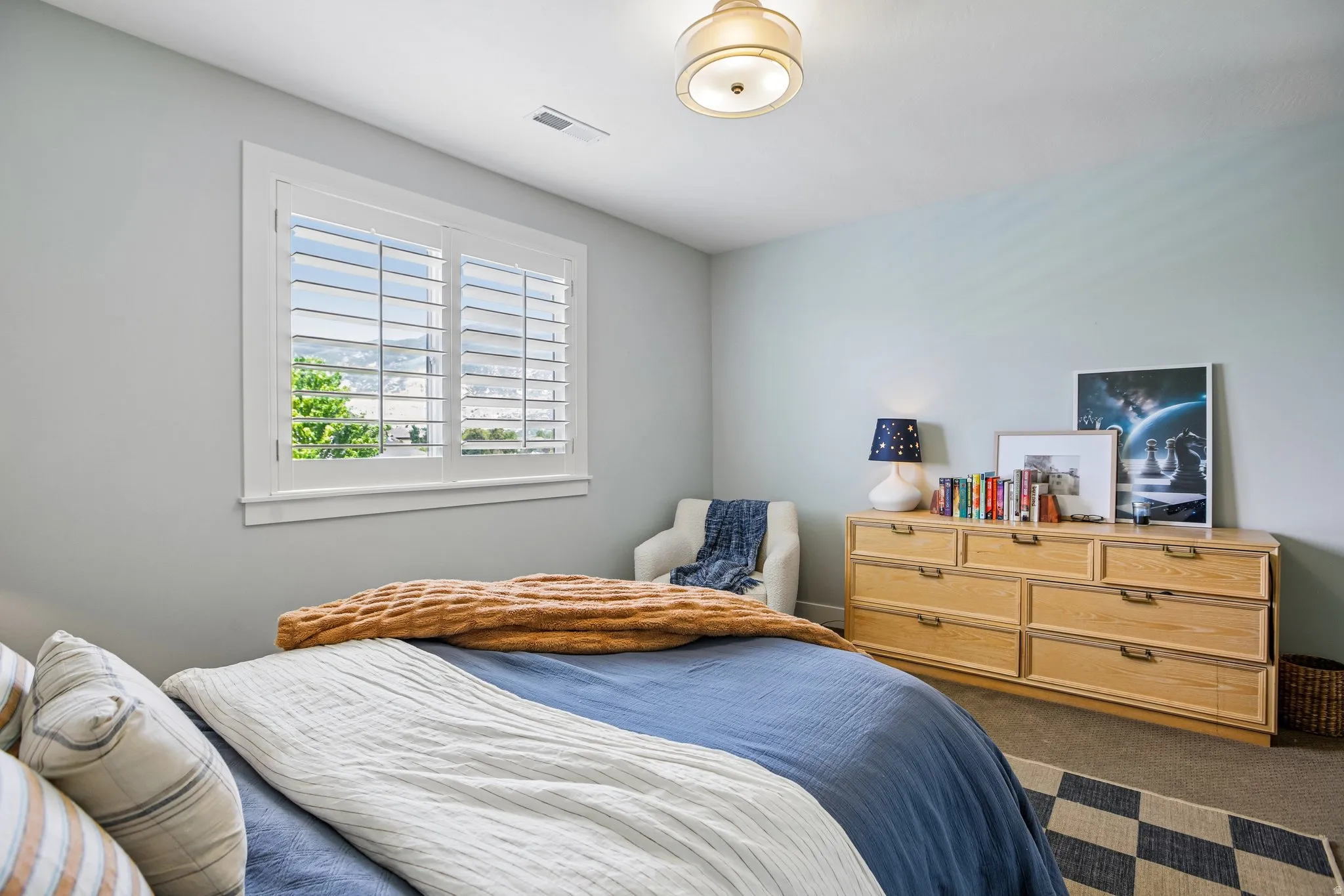 Bright room featuring a window with white louvered shutters, light-toned walls, and a semi-flush mount ceiling fixture