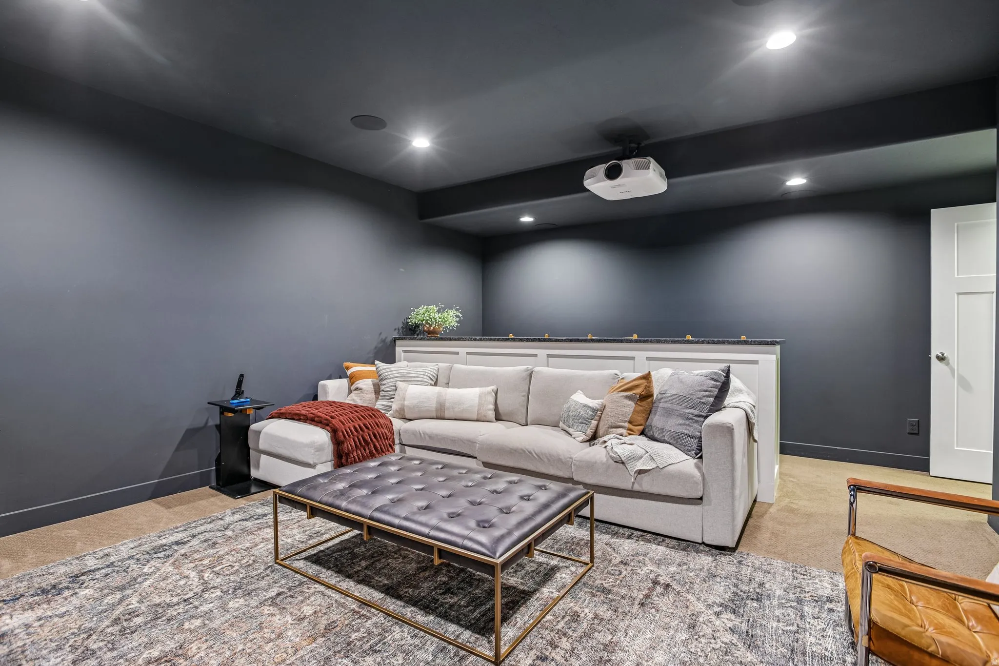 Media room with dark wall color, recessed lighting, and a mounted projector