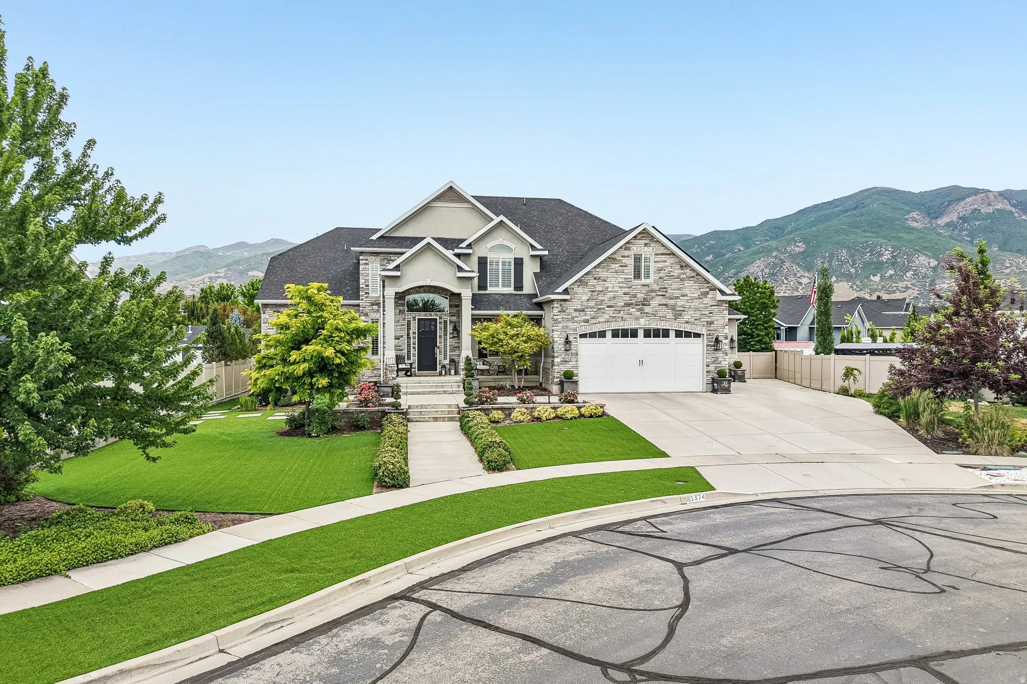 Stone and siding exterior with a prominent arched entry, two-car garage, and a steeply pitched roofline