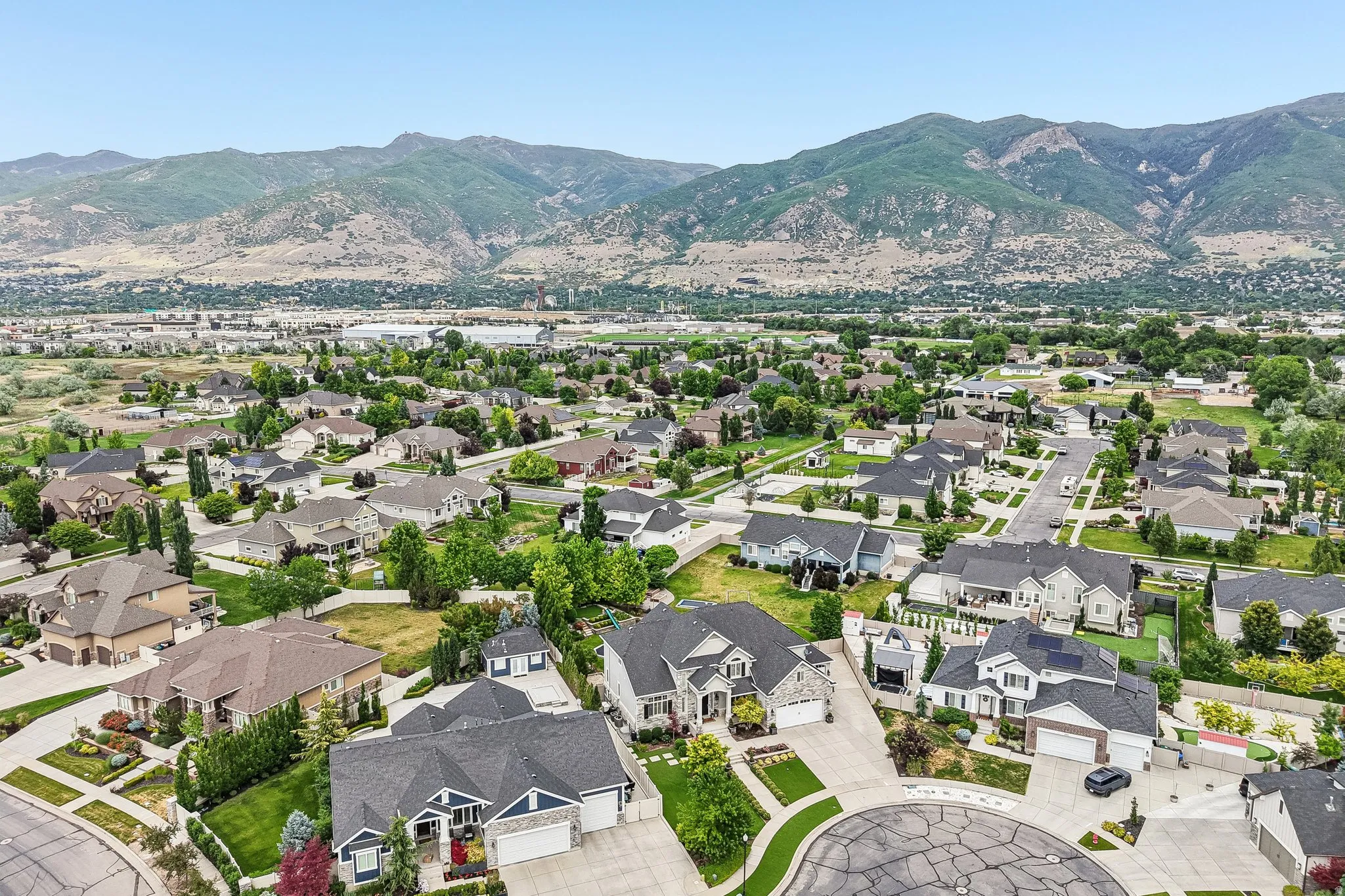 Aerial perspective of a residential neighborhood with varied architectural styles, manicured lawns, and mature trees