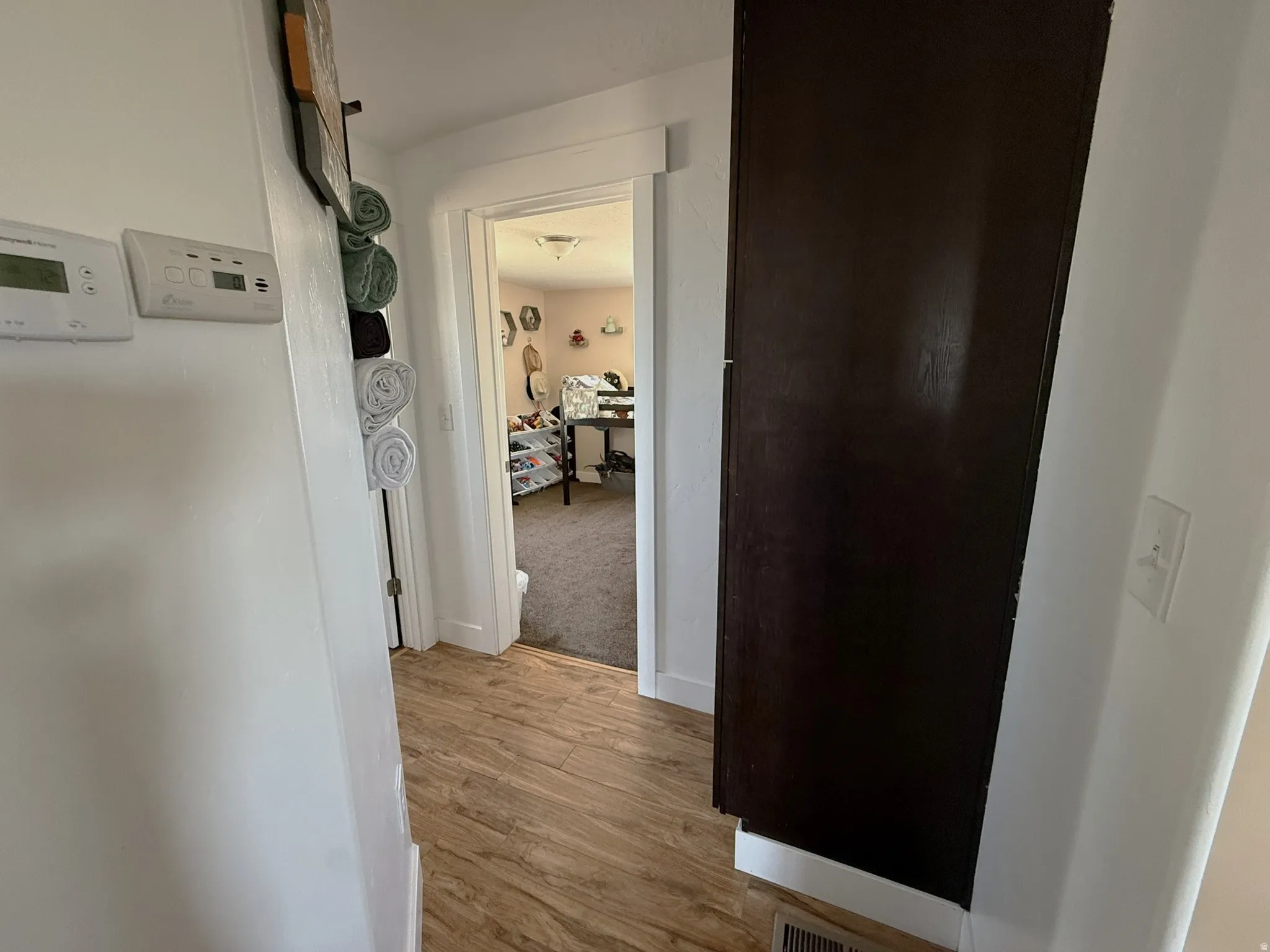 Hallway with wood-finish flooring, white walls, and a dark brown built-in cabinet
