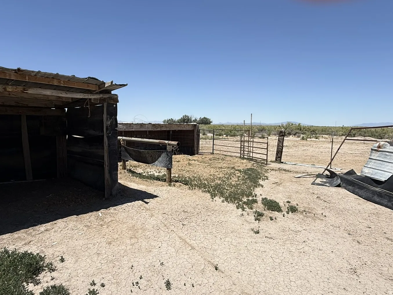 Outdoor fenced area featuring a wood-framed shelter and arid landscape