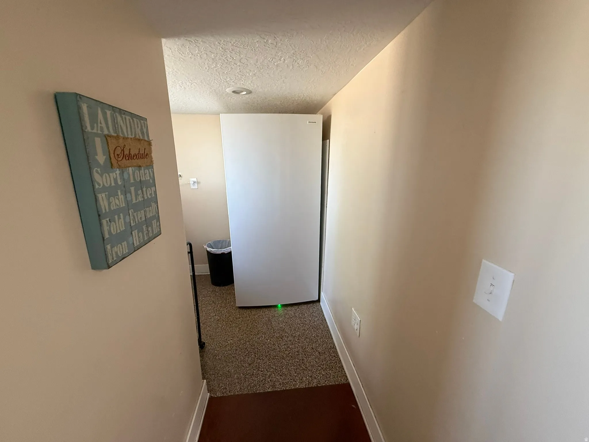 Laundry area featuring textured walls, recessed lighting, and durable speckled flooring
