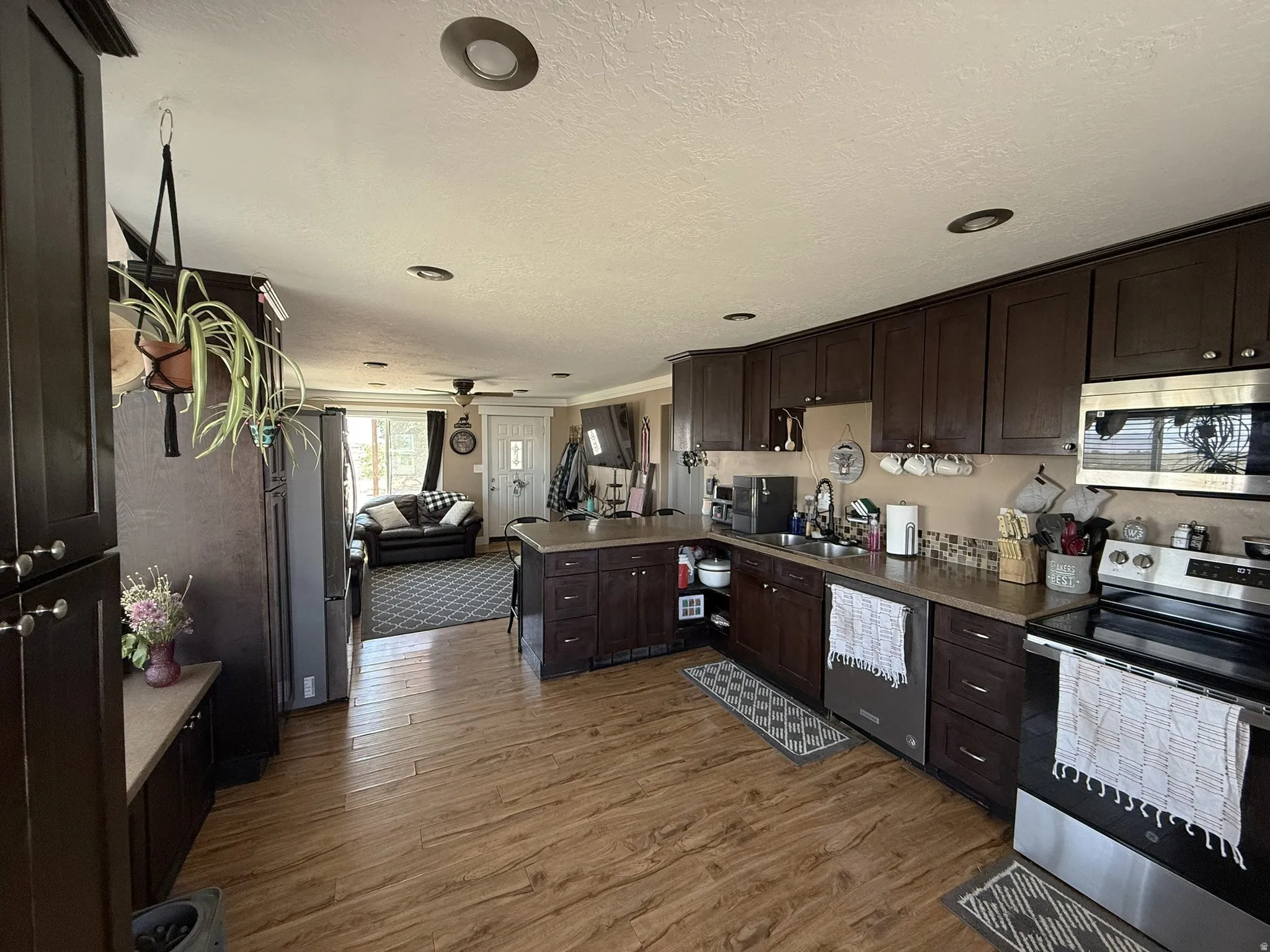 Kitchen featuring dark wood-finish cabinetry, stainless steel appliances, a tile backsplash, and light-toned countertops