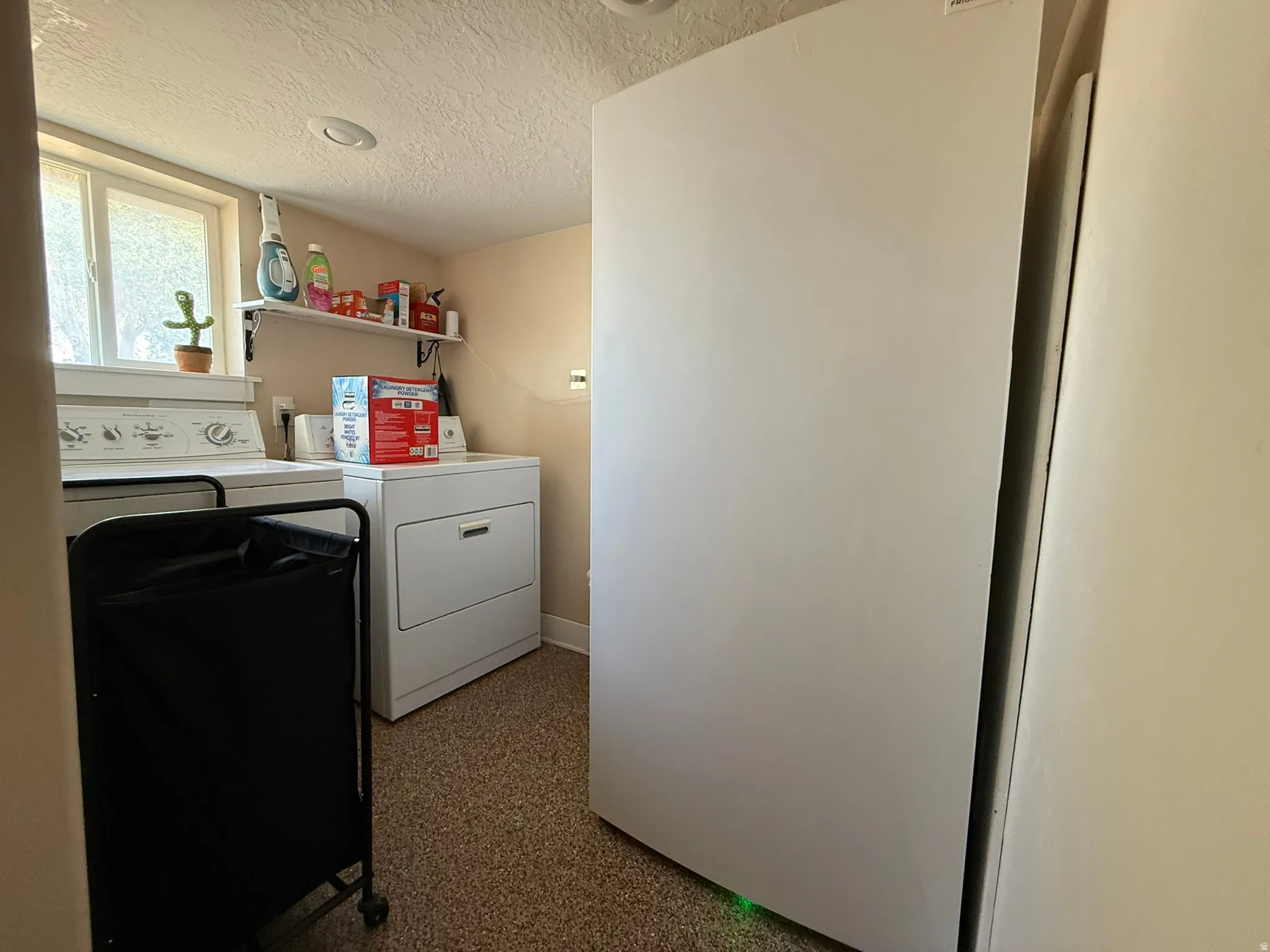Dedicated laundry area featuring a window, built-in shelving, overhead lighting, and resilient flooring