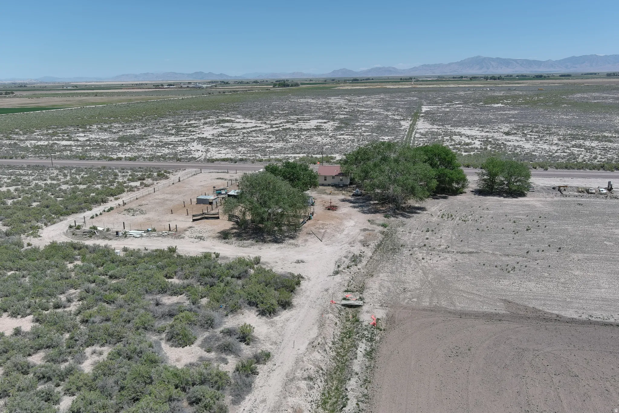 Rural property featuring a single-story residence, mature trees, and expansive undeveloped land