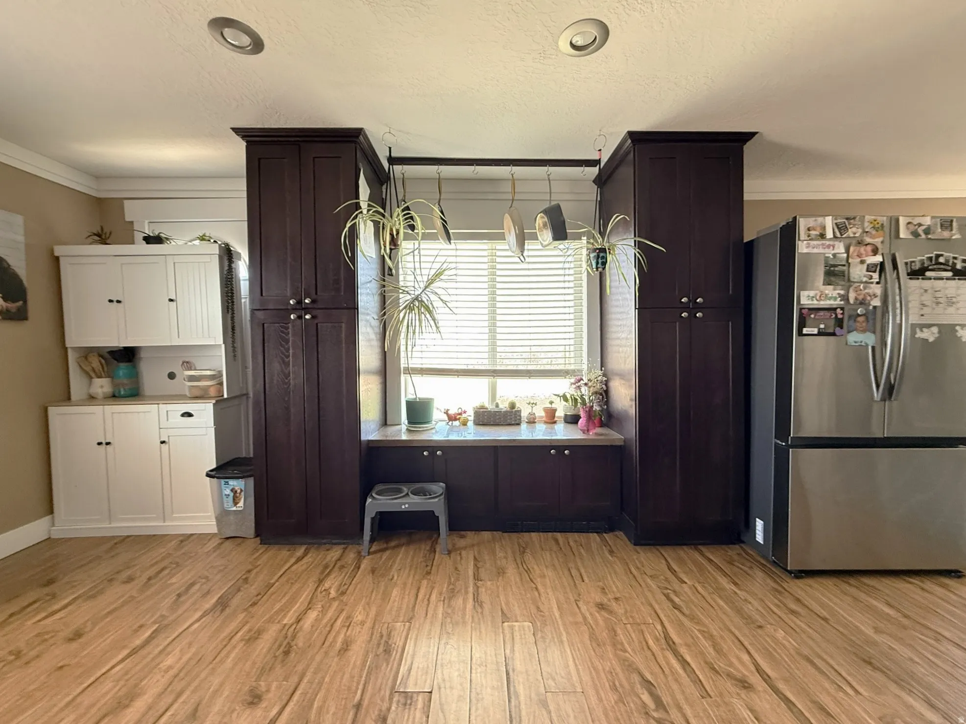 Spacious kitchen area featuring wood-finish flooring, recessed lighting, and a window with blinds