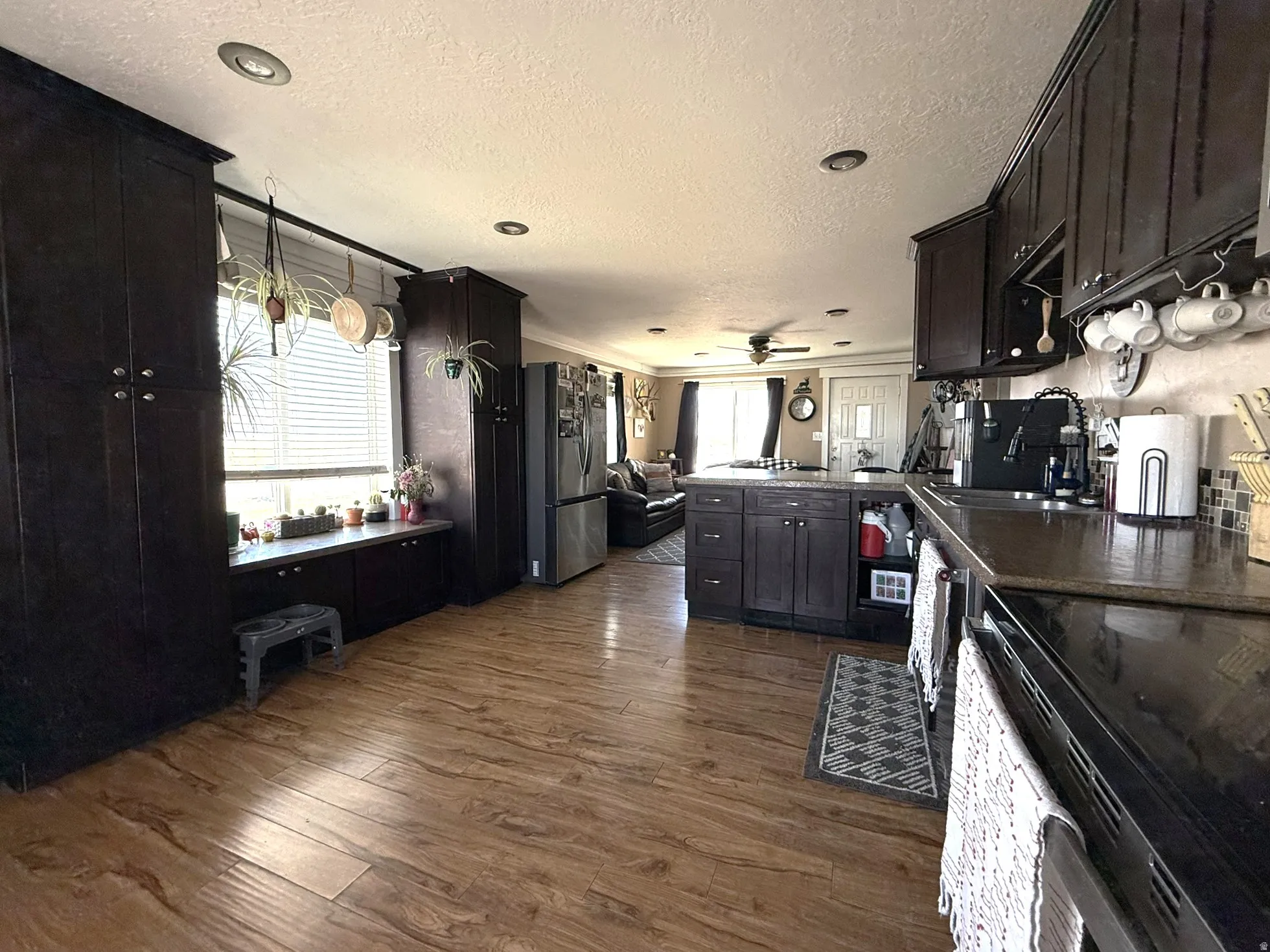 Spacious kitchen featuring dark wood-finish cabinetry, wood-finish flooring, a central island with countertop, and recessed ceiling lighting