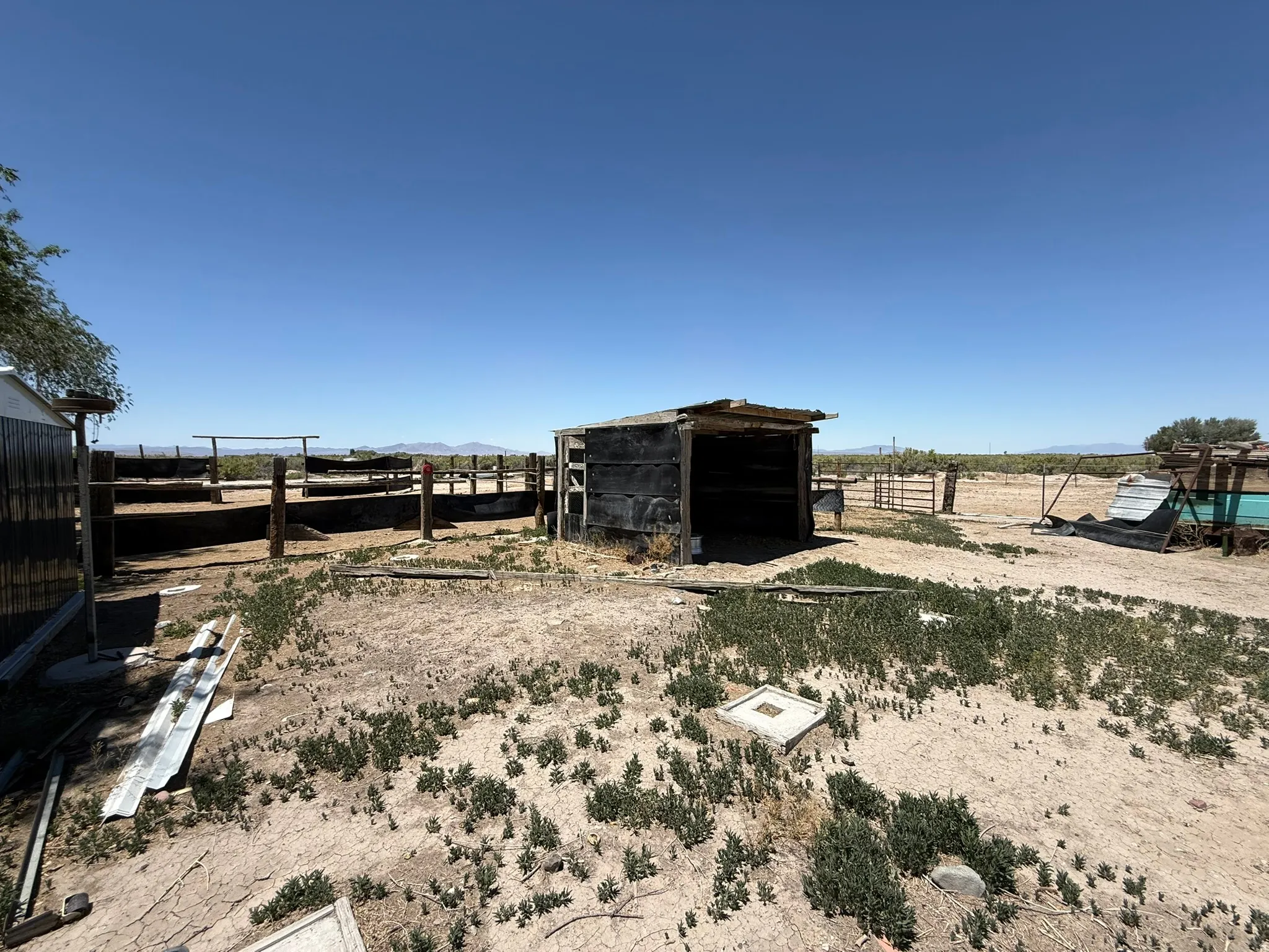 Rustic outbuilding with open frontage, surrounded by a fenced corral area