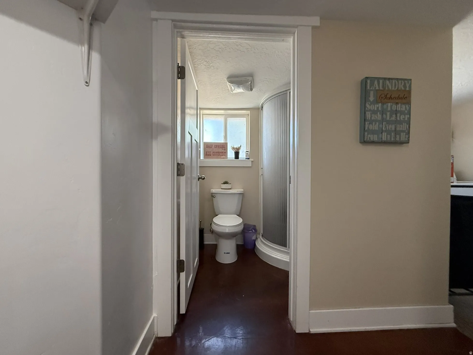 Bathroom featuring a white toilet, frosted glass shower enclosure, and a window providing natural light