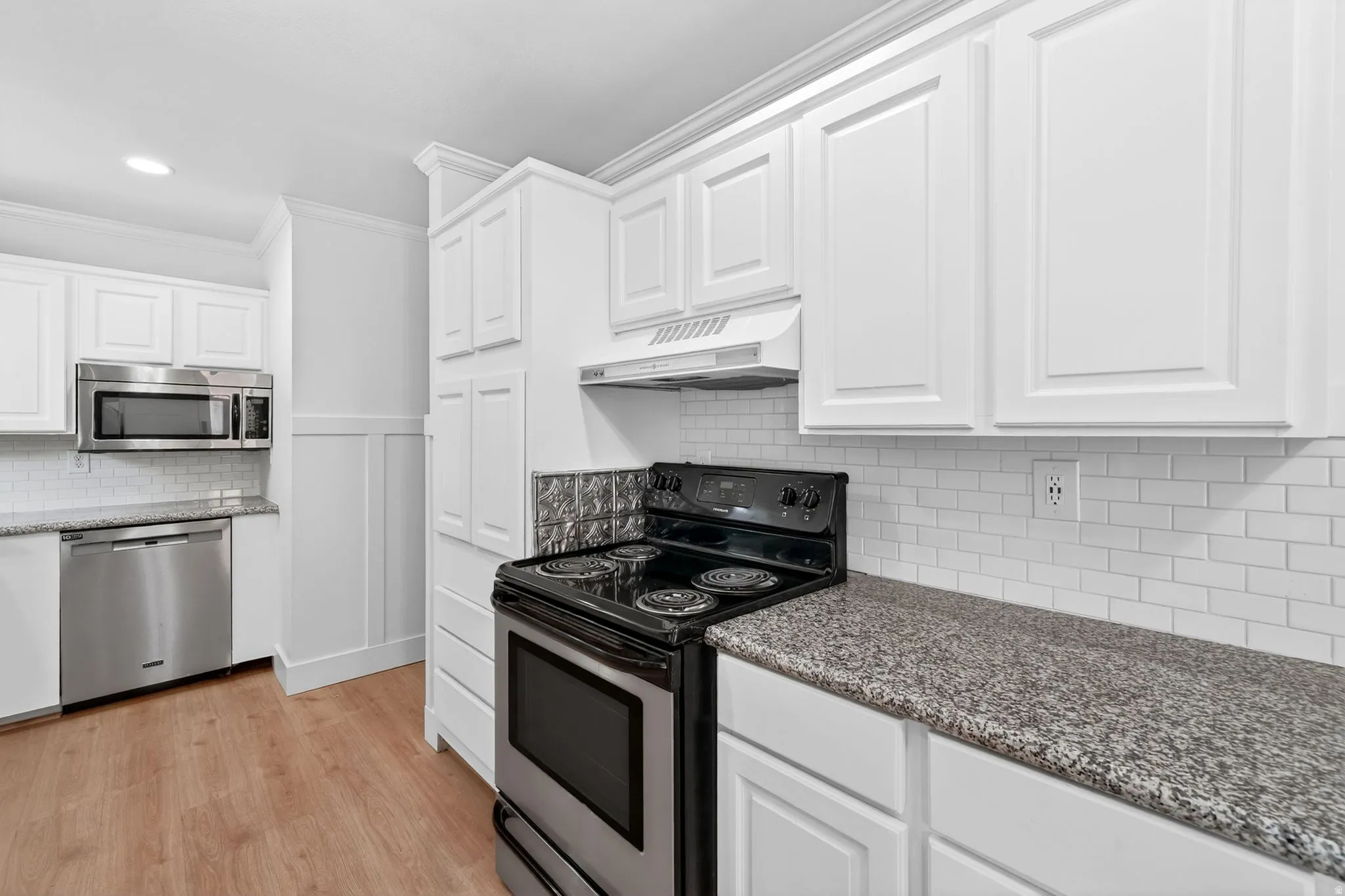 Kitchen featuring white shaker-style cabinetry, wood-finish flooring, granite countertops, and a white subway tile backsplash