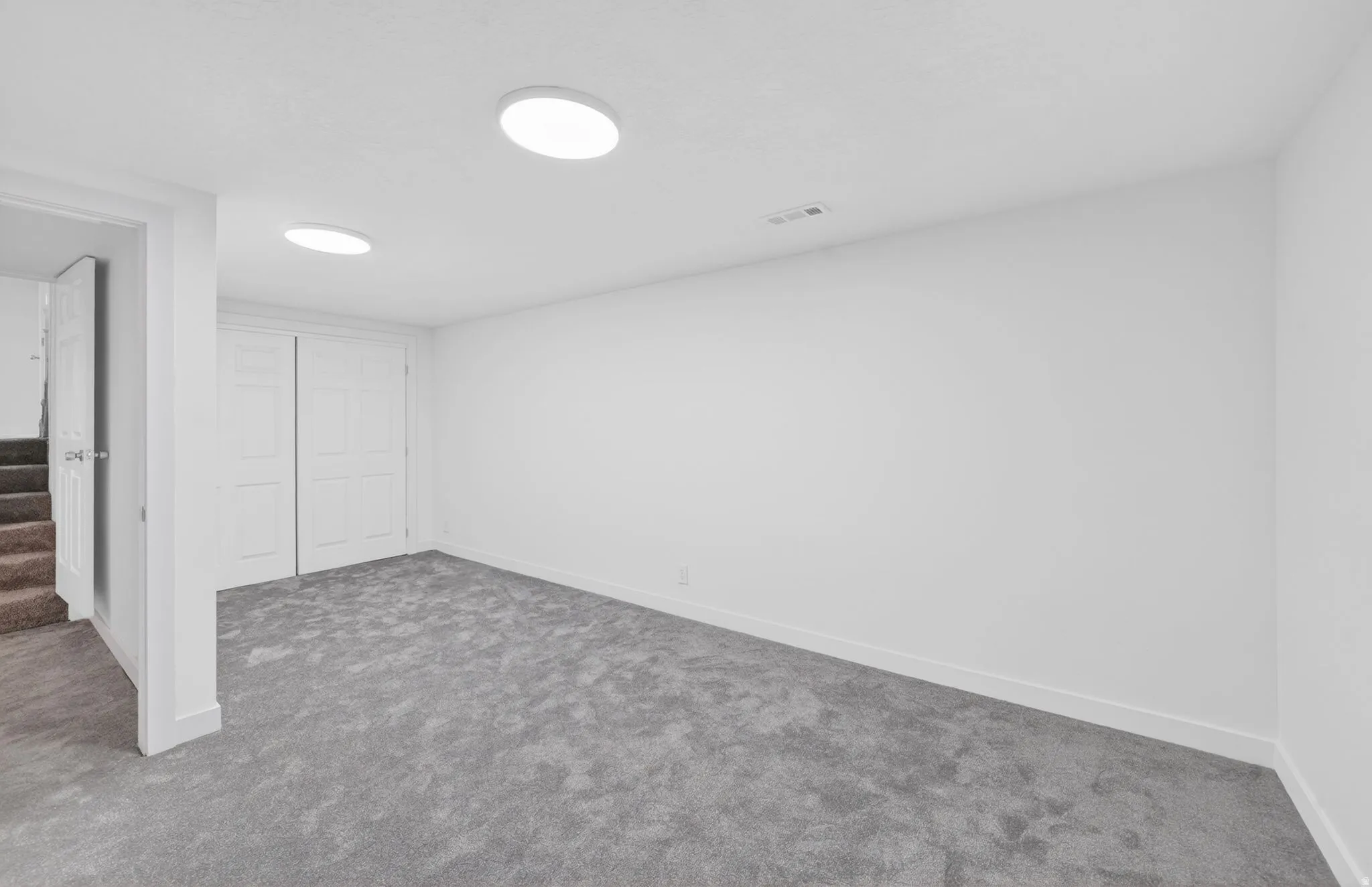 Open room featuring light gray carpeting and white walls