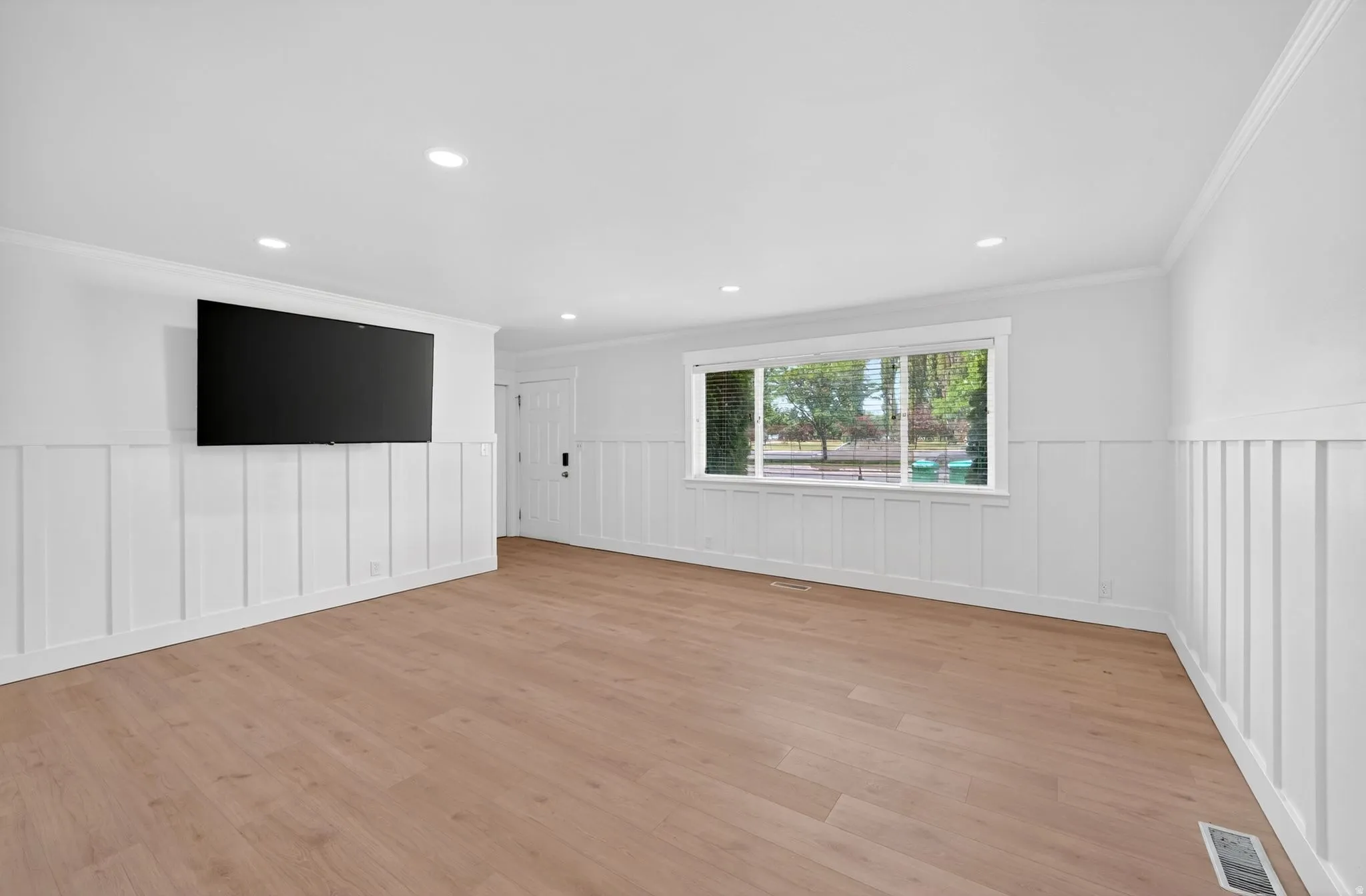 Spacious room featuring wood-finish flooring and board-and-batten accent walls