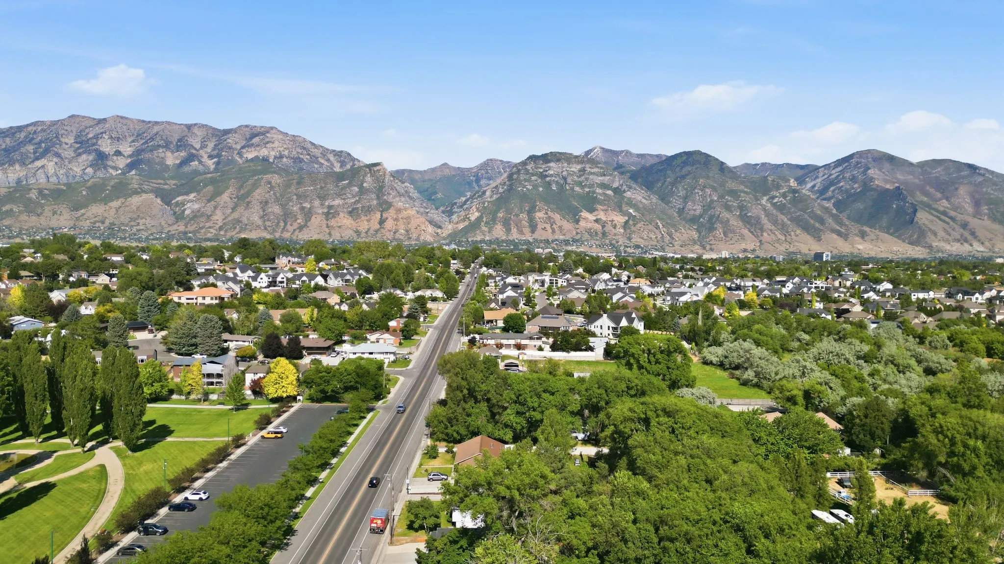 Expansive neighborhood setting featuring a prominent roadway, surrounding residential structures, and abundant mature trees