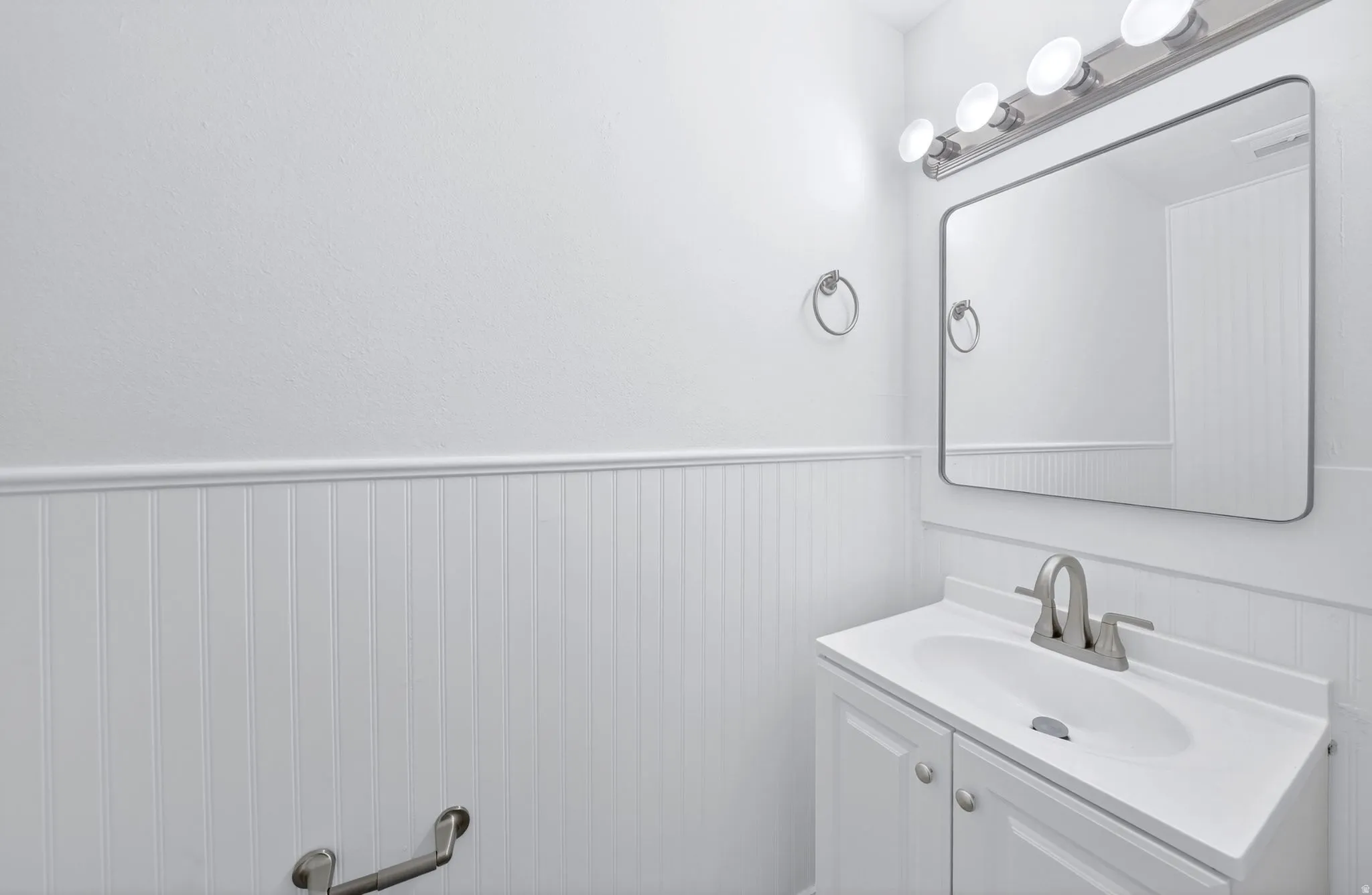 White vanity with integrated sink, brushed nickel faucet, and coordinating hardware