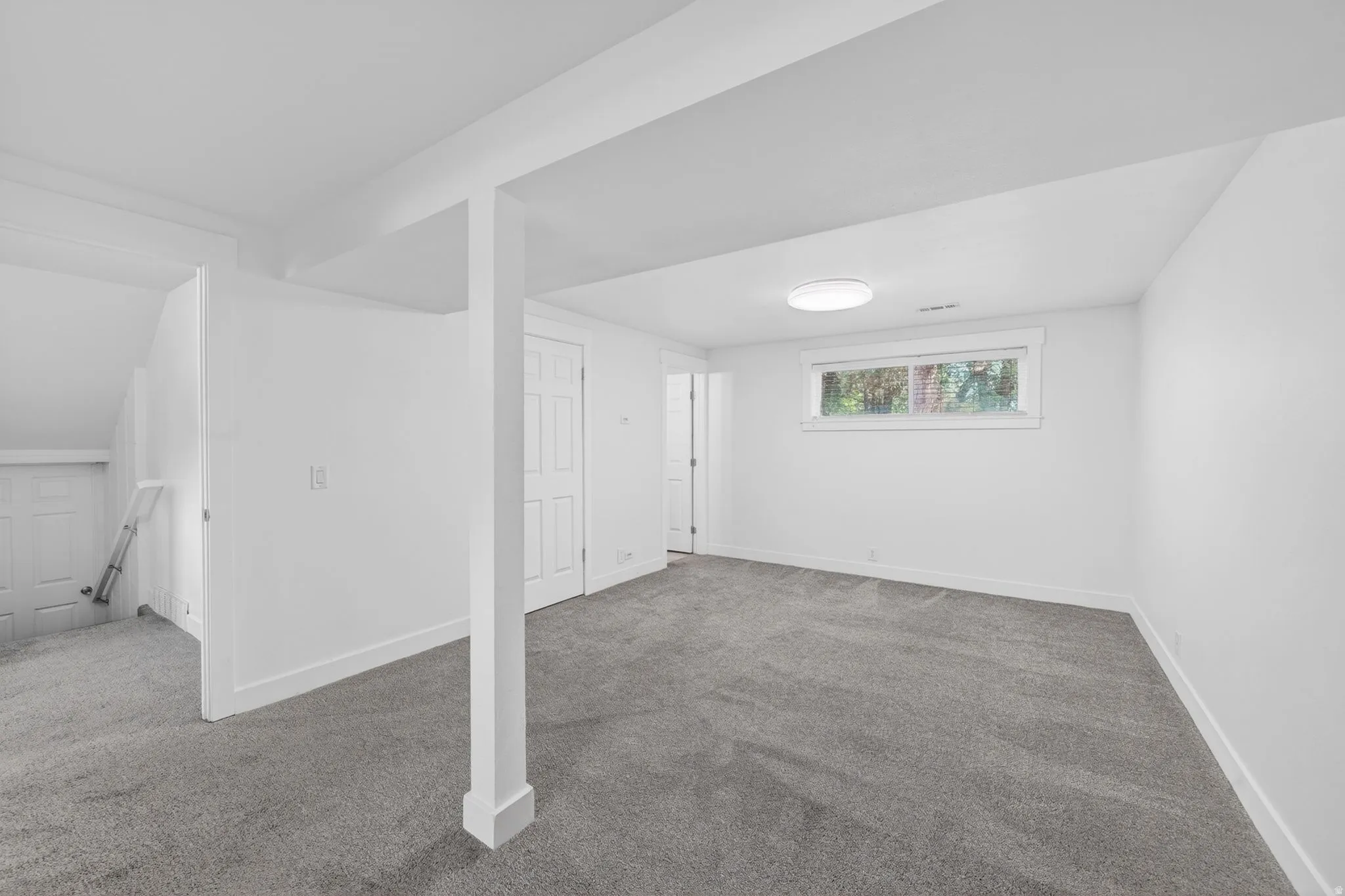 Bright room featuring soft gray carpeting, white walls, and a prominent white support column
