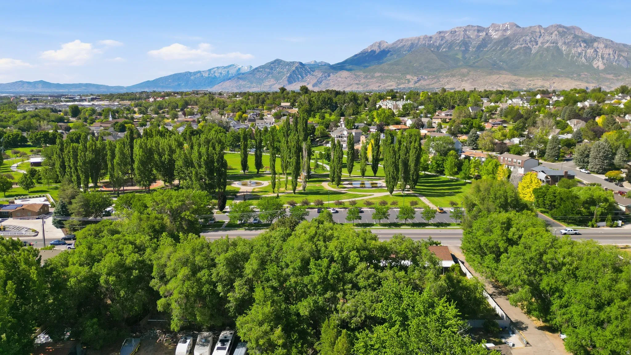 Expansive green space featuring mature trees and a manicured park with established walking paths
