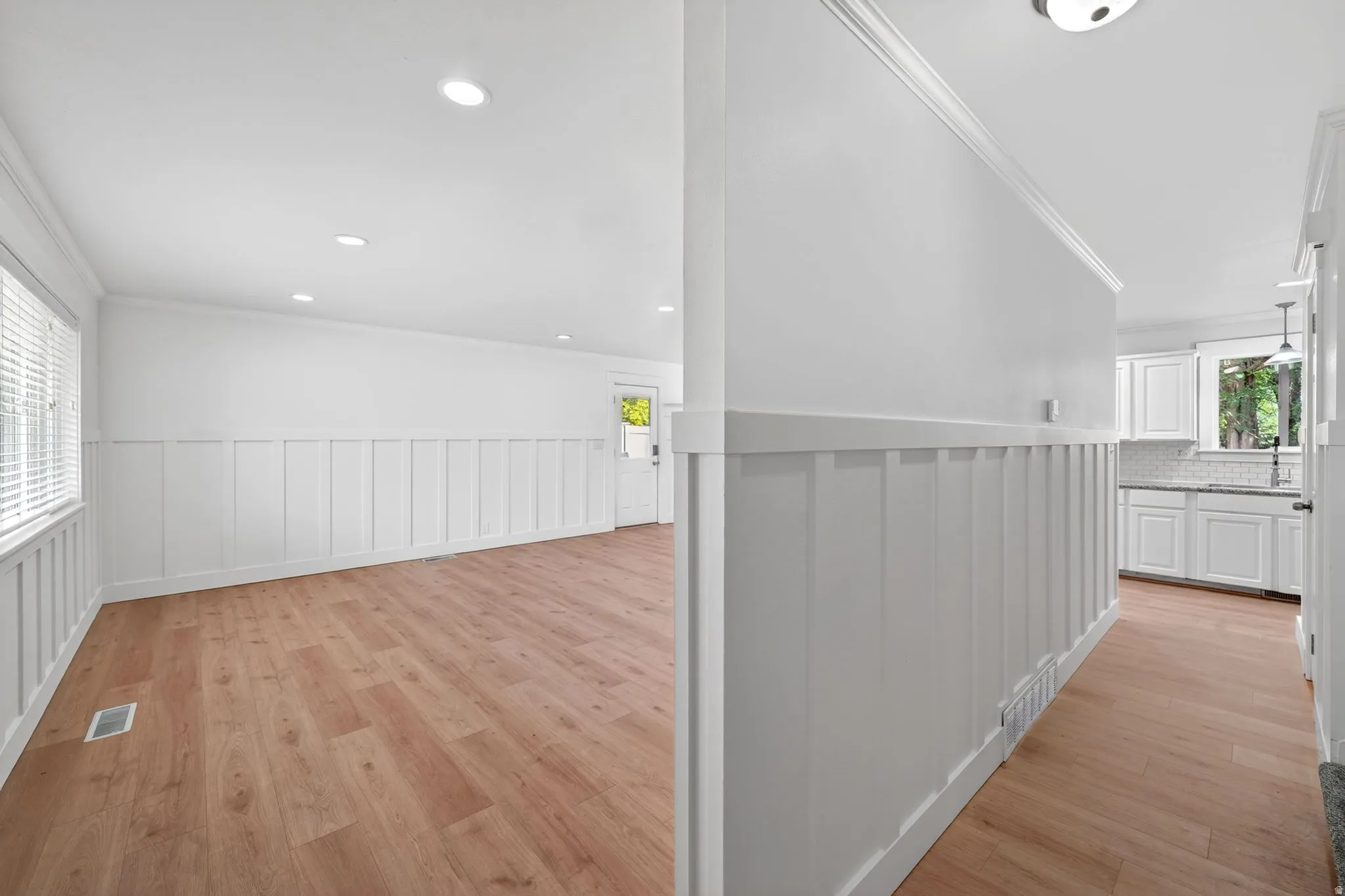 Open concept living area featuring wood-finish flooring, recessed lighting, and white board and batten wall detailing