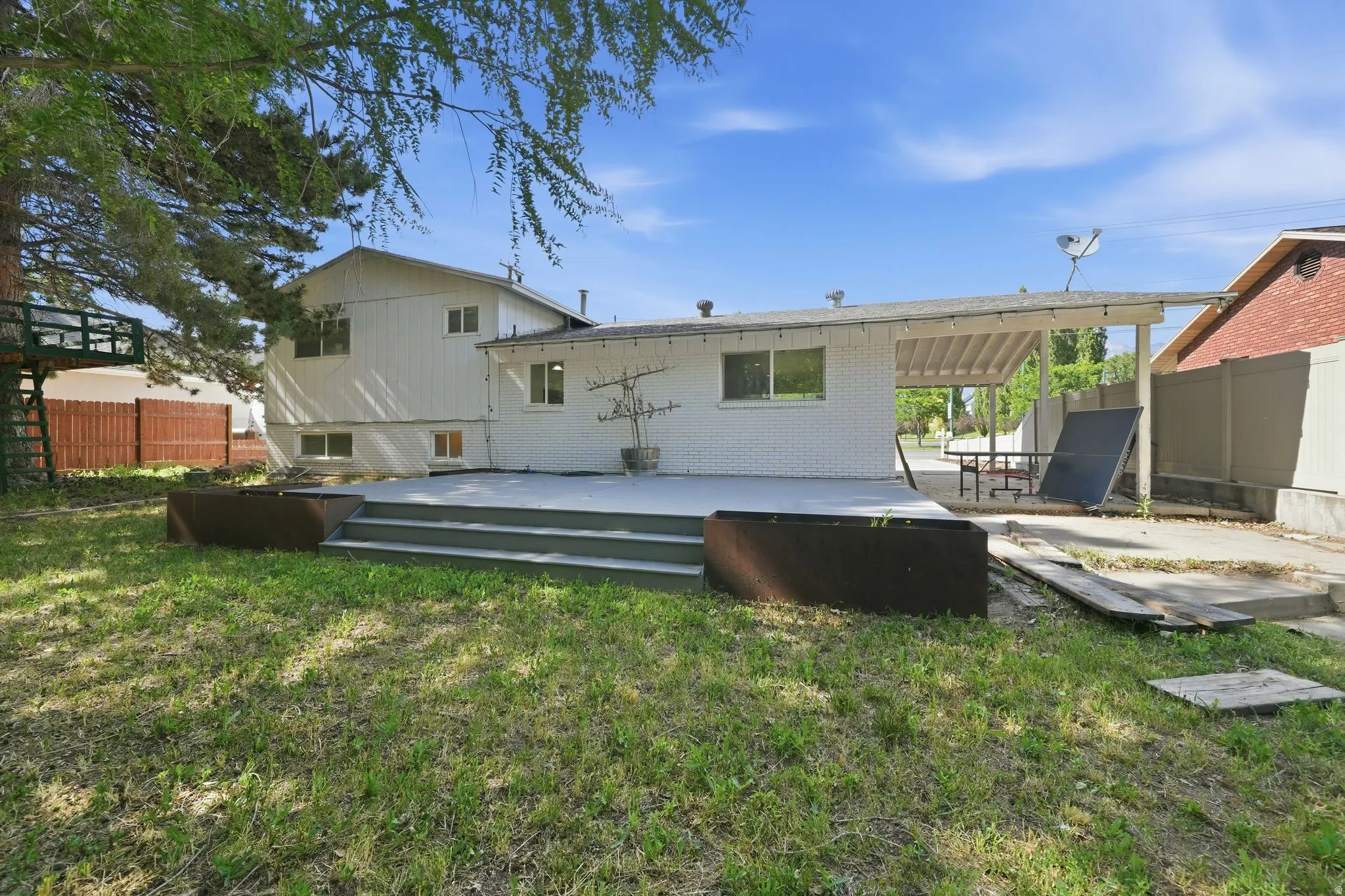 Expansive backyard featuring a multi-level deck, covered patio, and mature perimeter trees