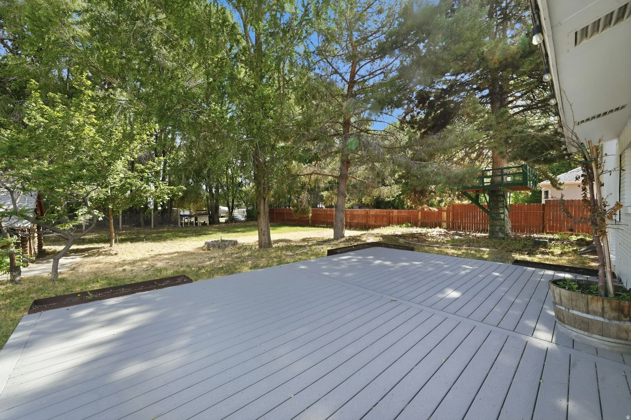 Expansive grey-toned composite decking overlooking a private yard with mature trees