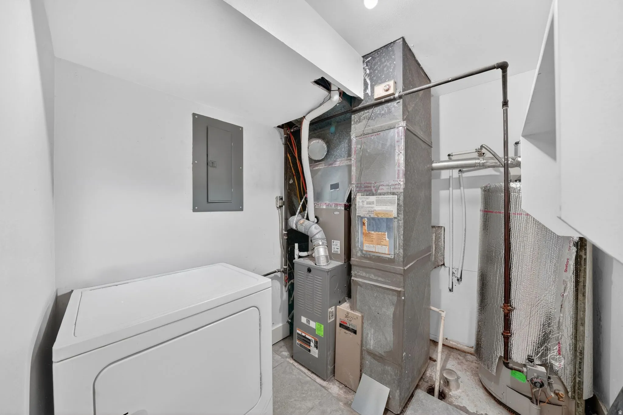 Utility area featuring a water heater, furnace, and exposed ductwork